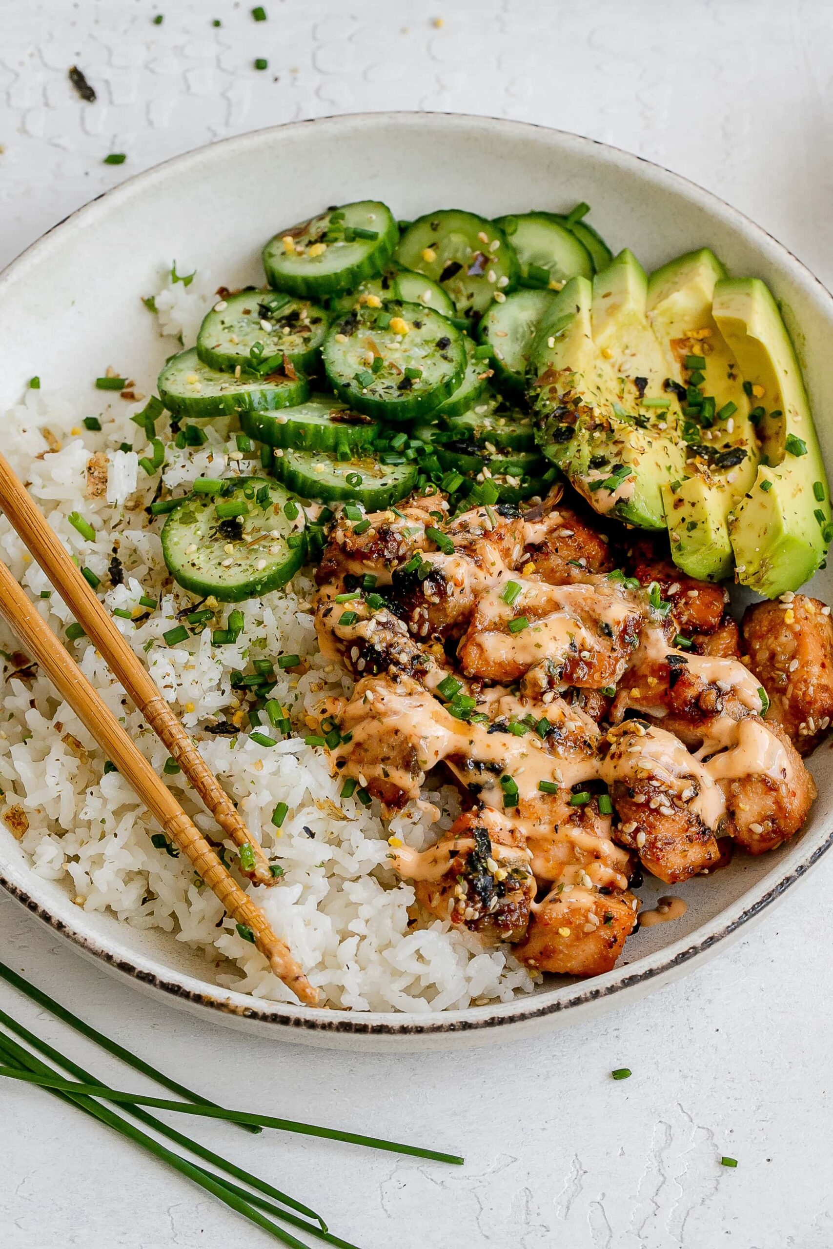 spicy salmon bowl with rice and pickled cucumbers.