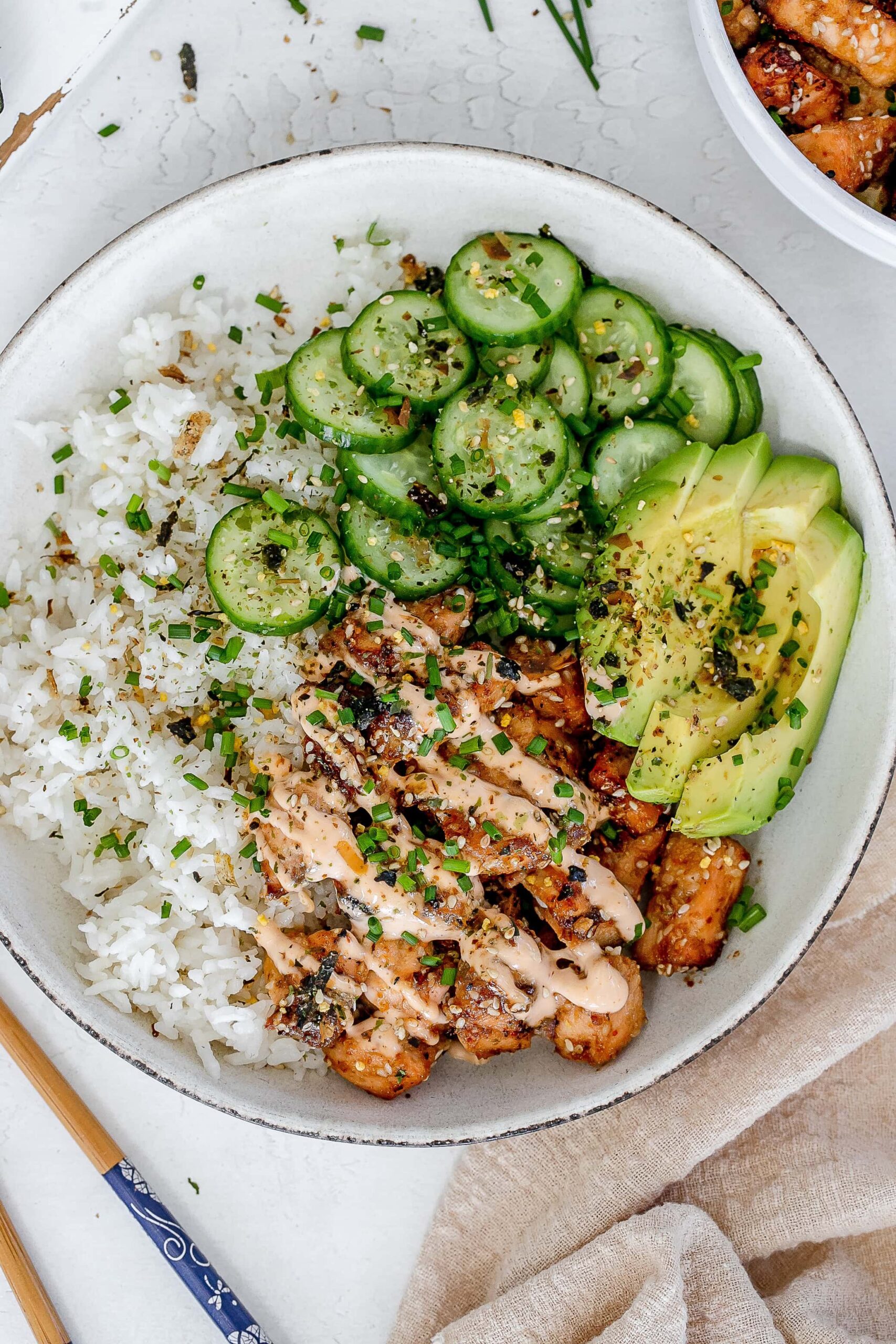 spicy salmon bowl with rice and pickled cucumbers.
