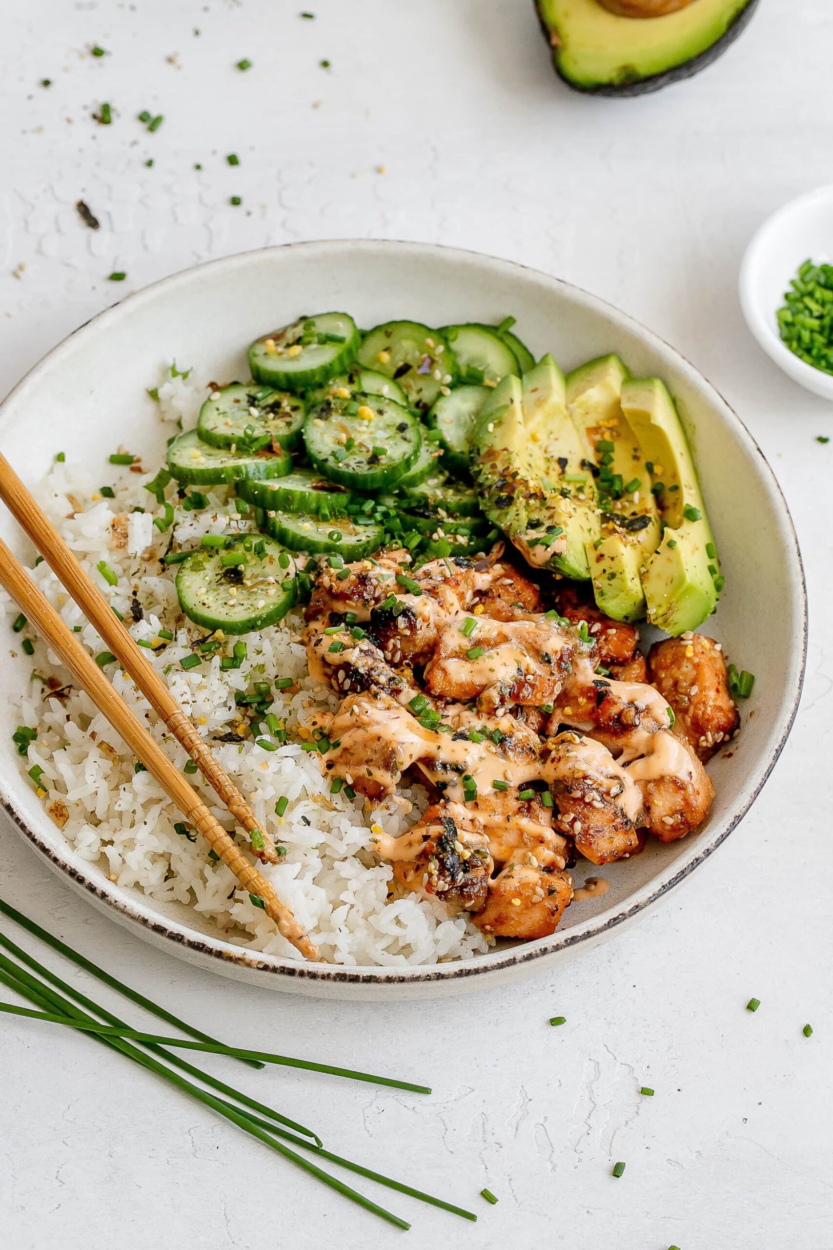 spicy salmon bowl with rice and pickled cucumbers.