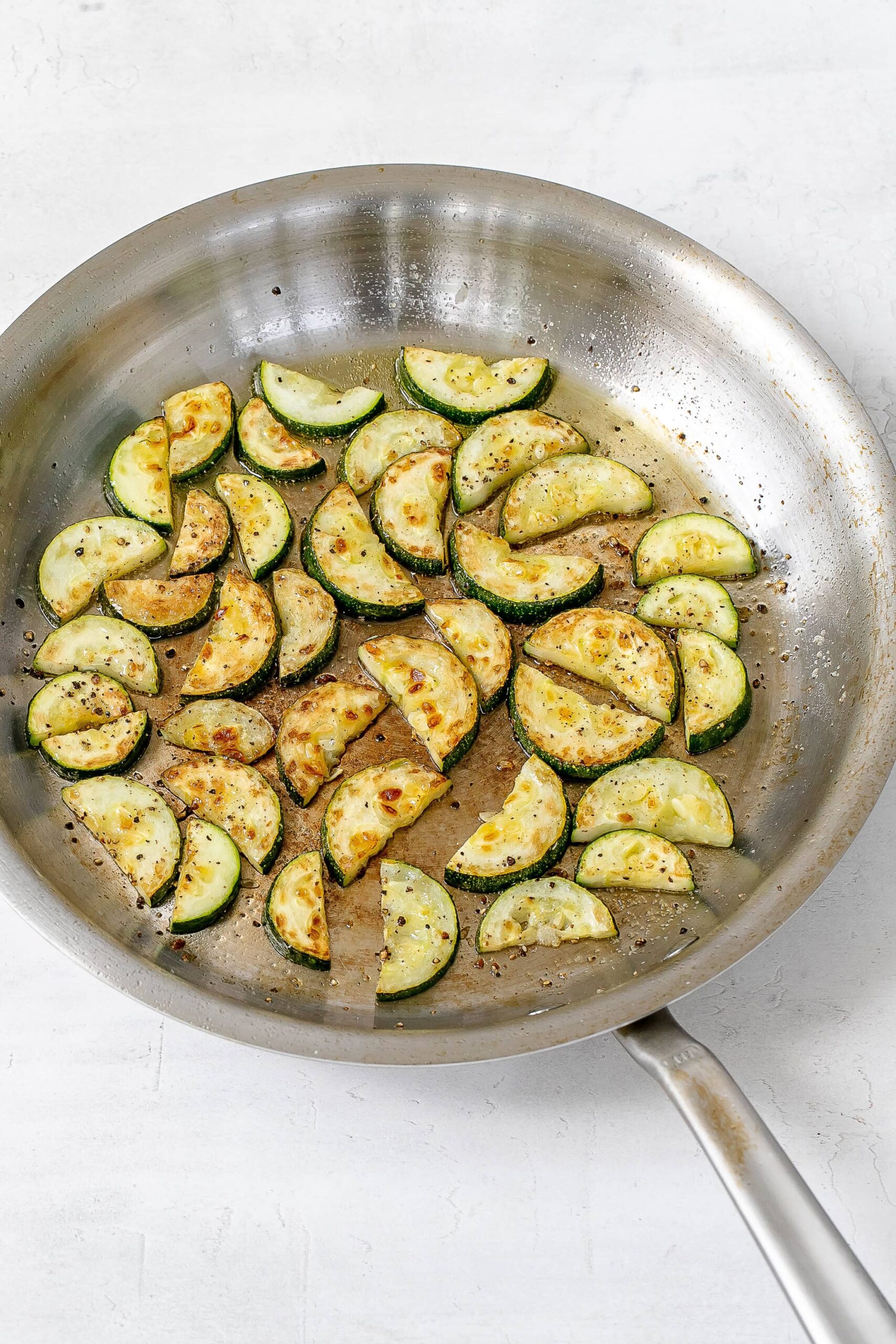 half moon cooked zucchini in skillet.