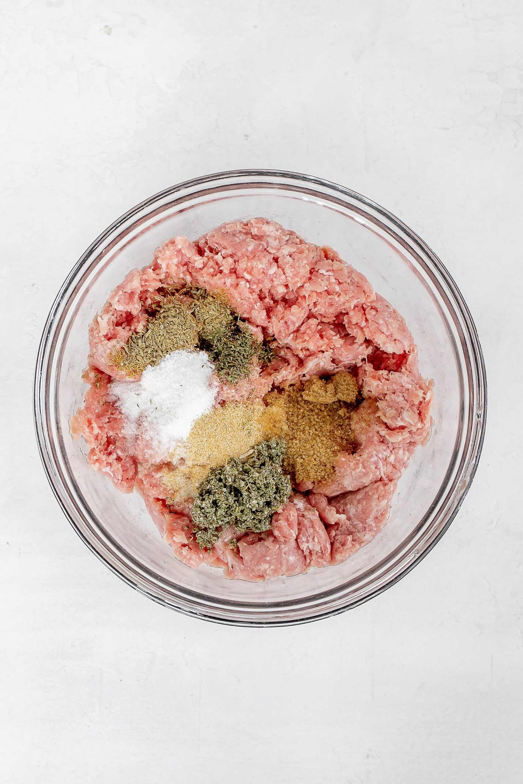 ground pork in bowl with spices for meatballs.