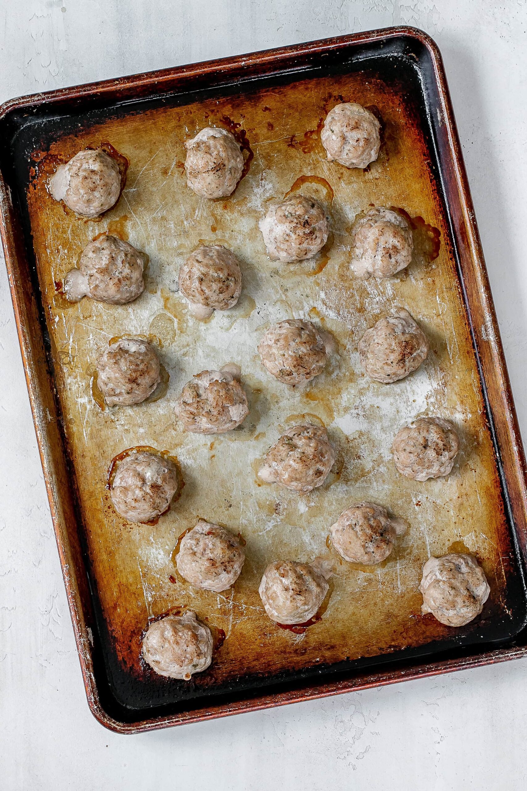 cooked pork meatballs on baking sheet.