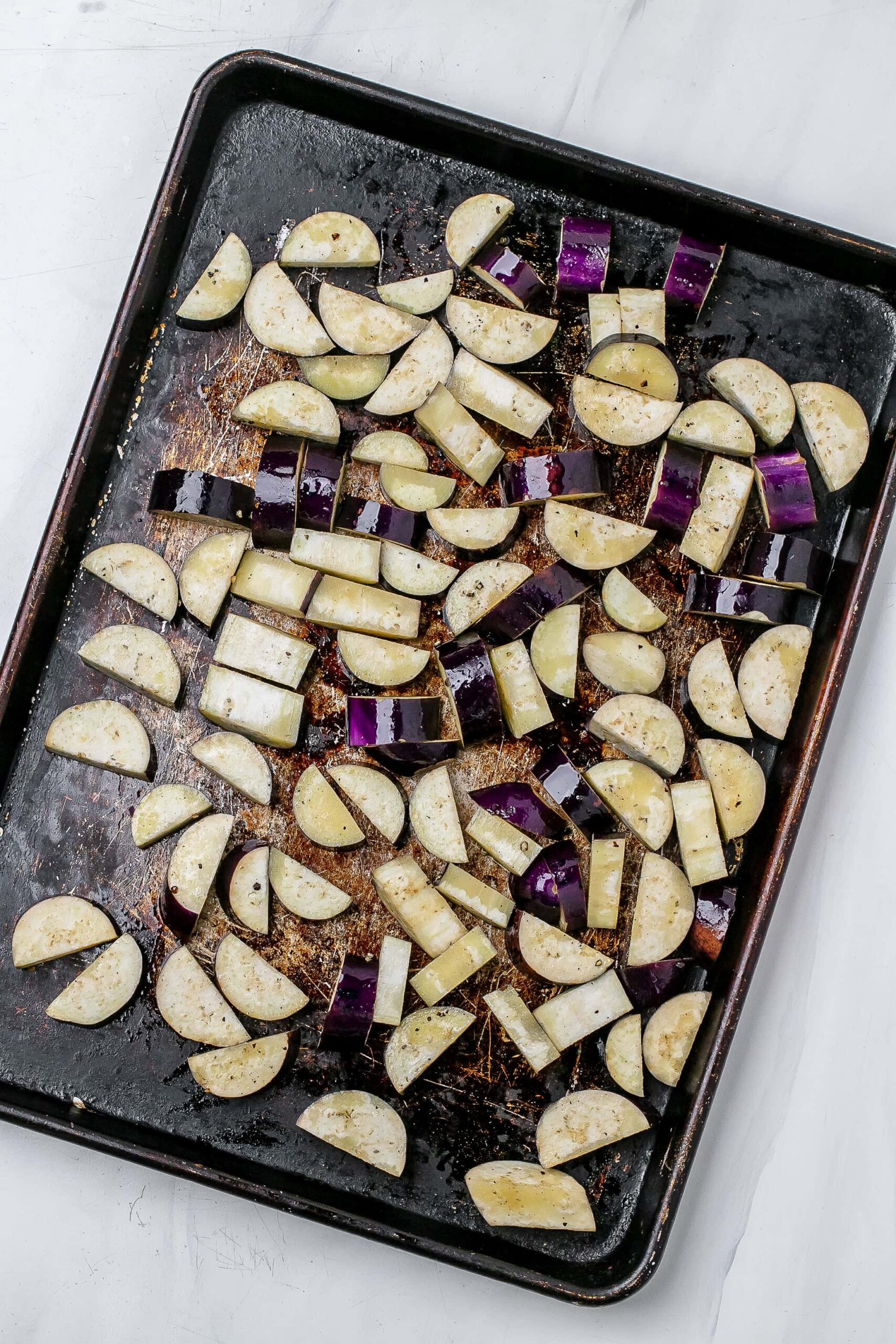raw eggplant half moons on baking sheet.