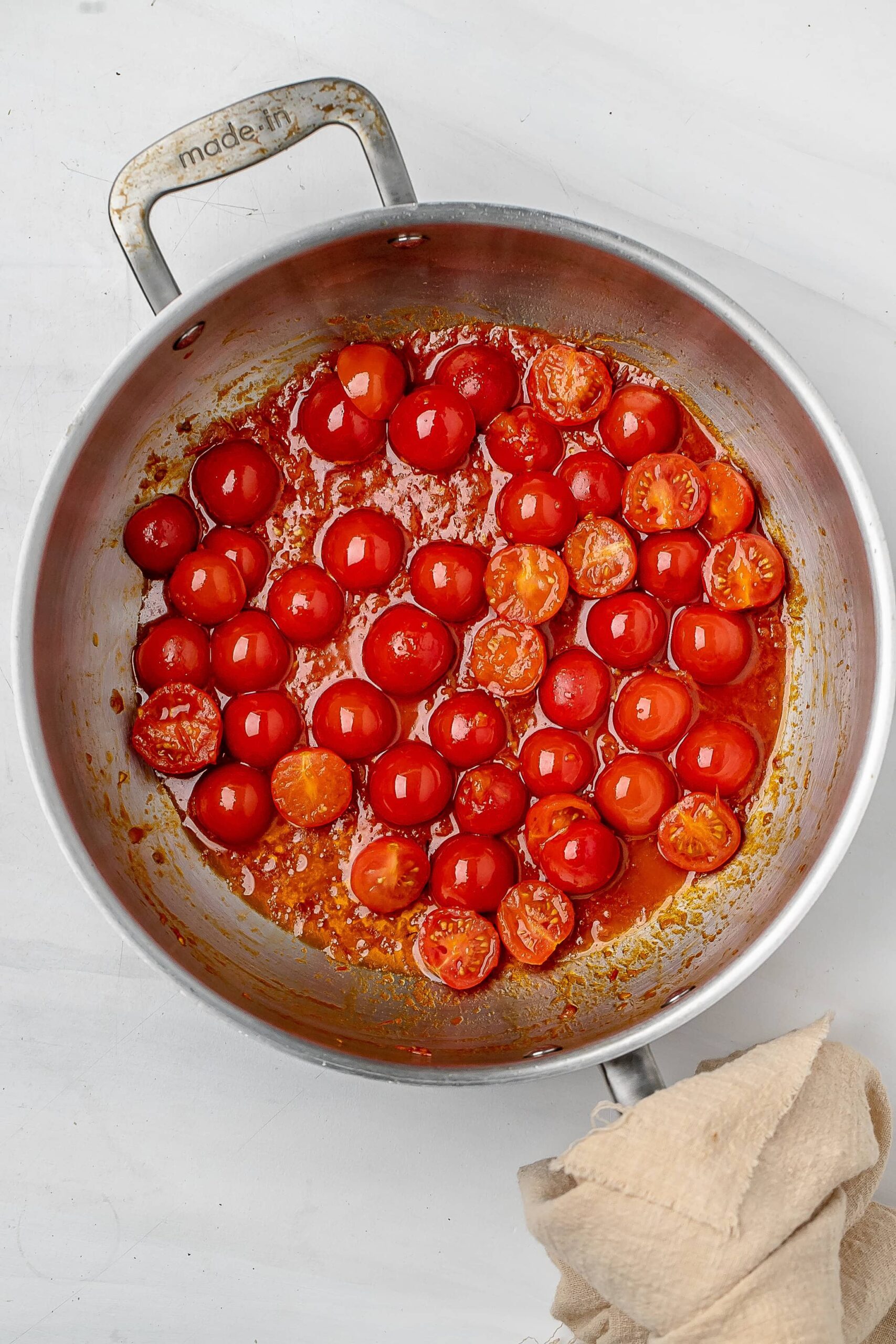 cherry tomatoes cooking in a pan with harissa.