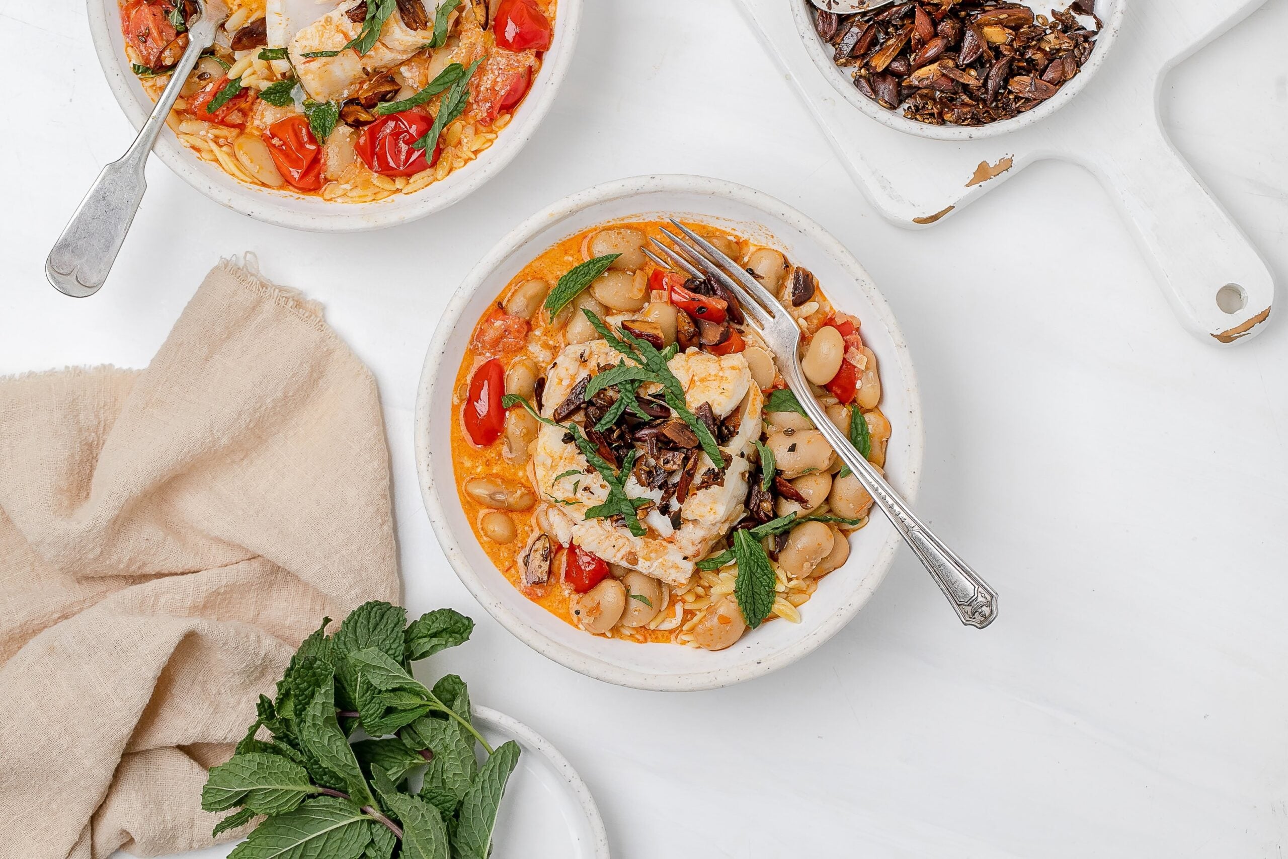 harissa cod poached in coconut milk in a bowl with orzo.