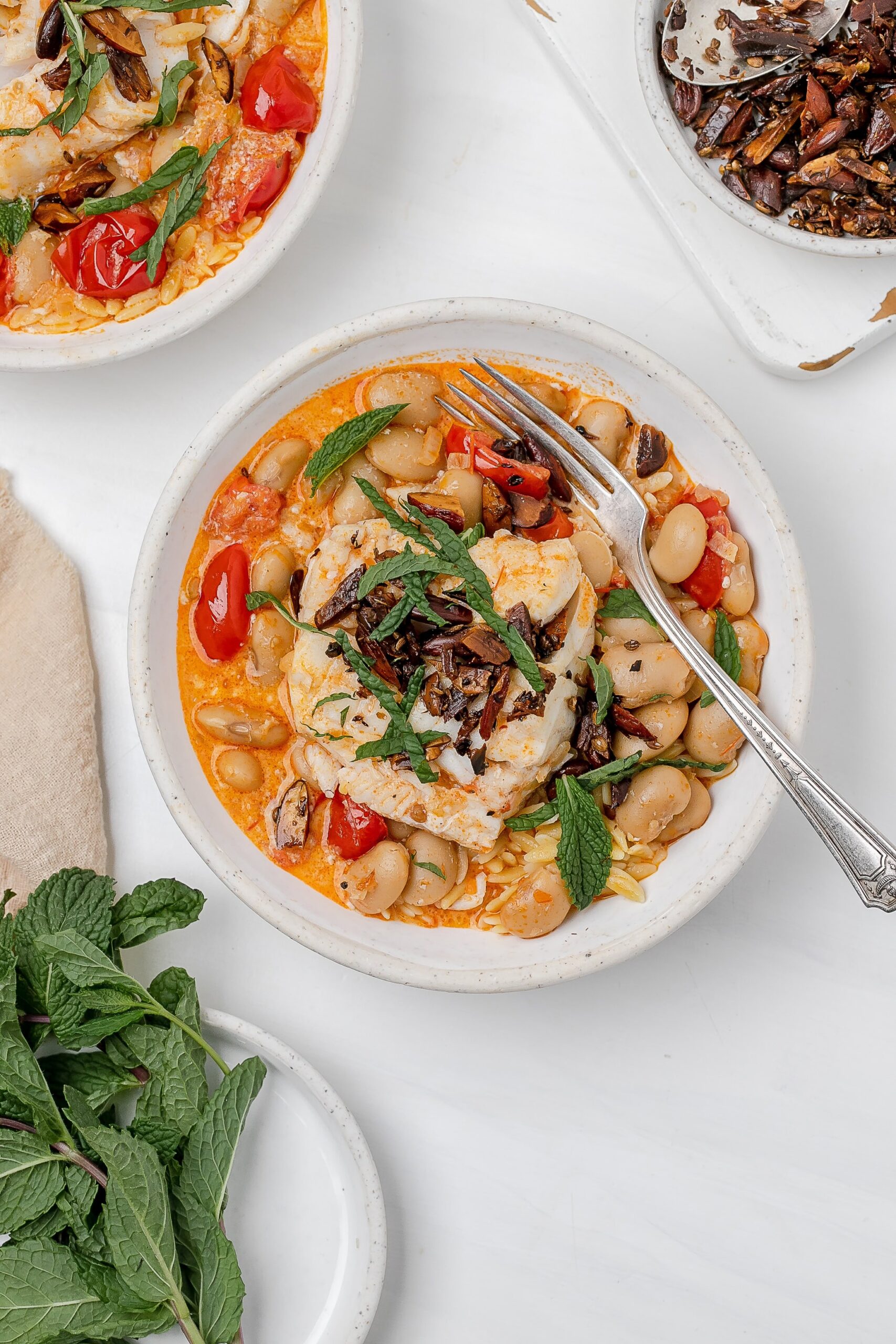 harissa cod poached in coconut milk in a bowl with orzo.