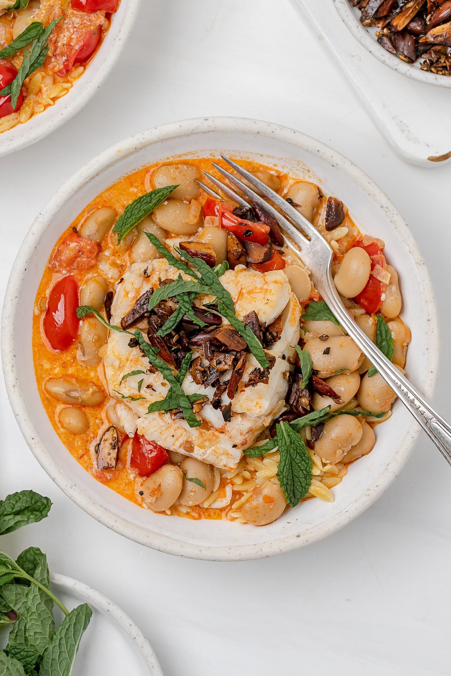 harissa cod poached in coconut milk in a bowl with orzo.