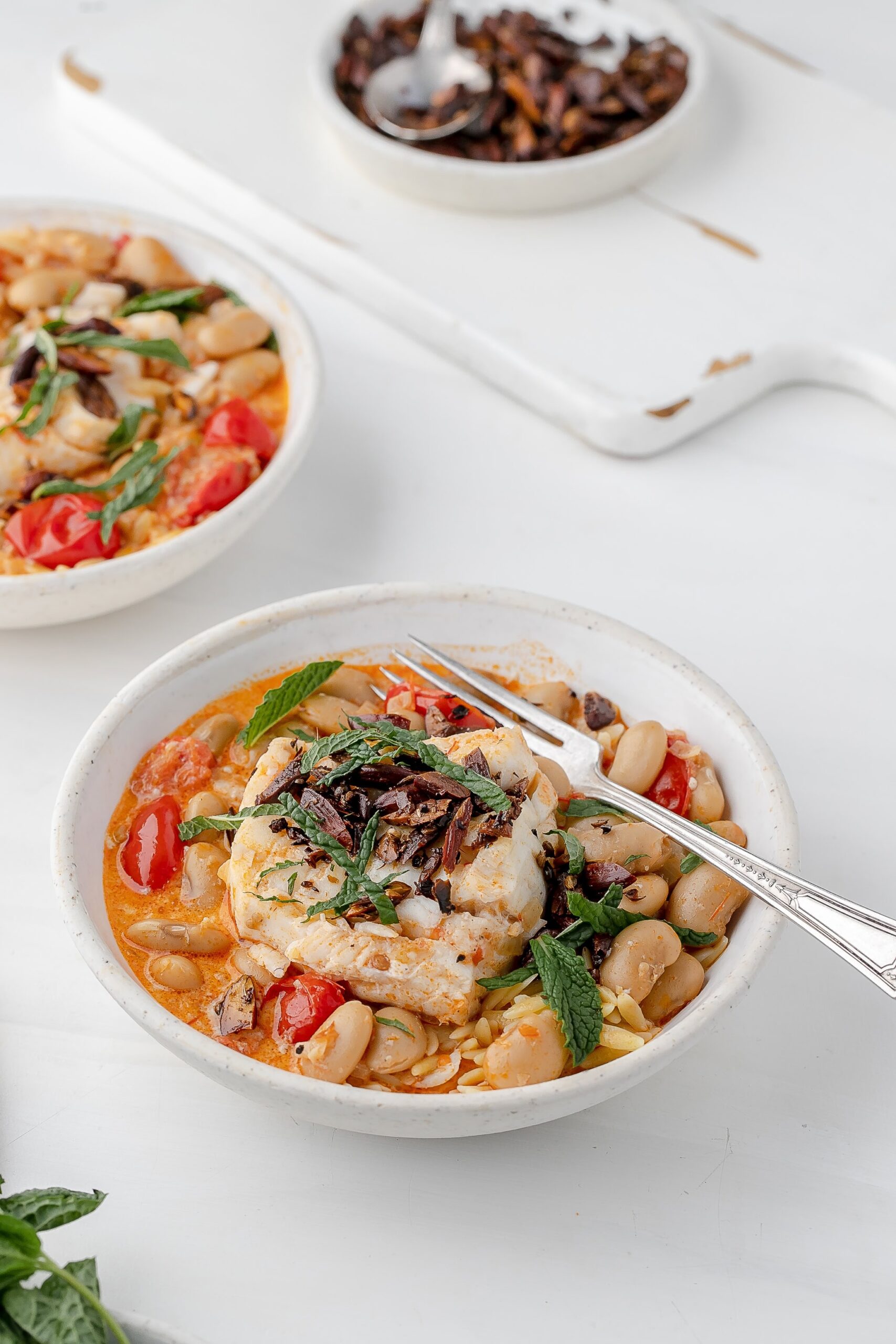 harissa cod poached in coconut milk in a bowl with orzo.