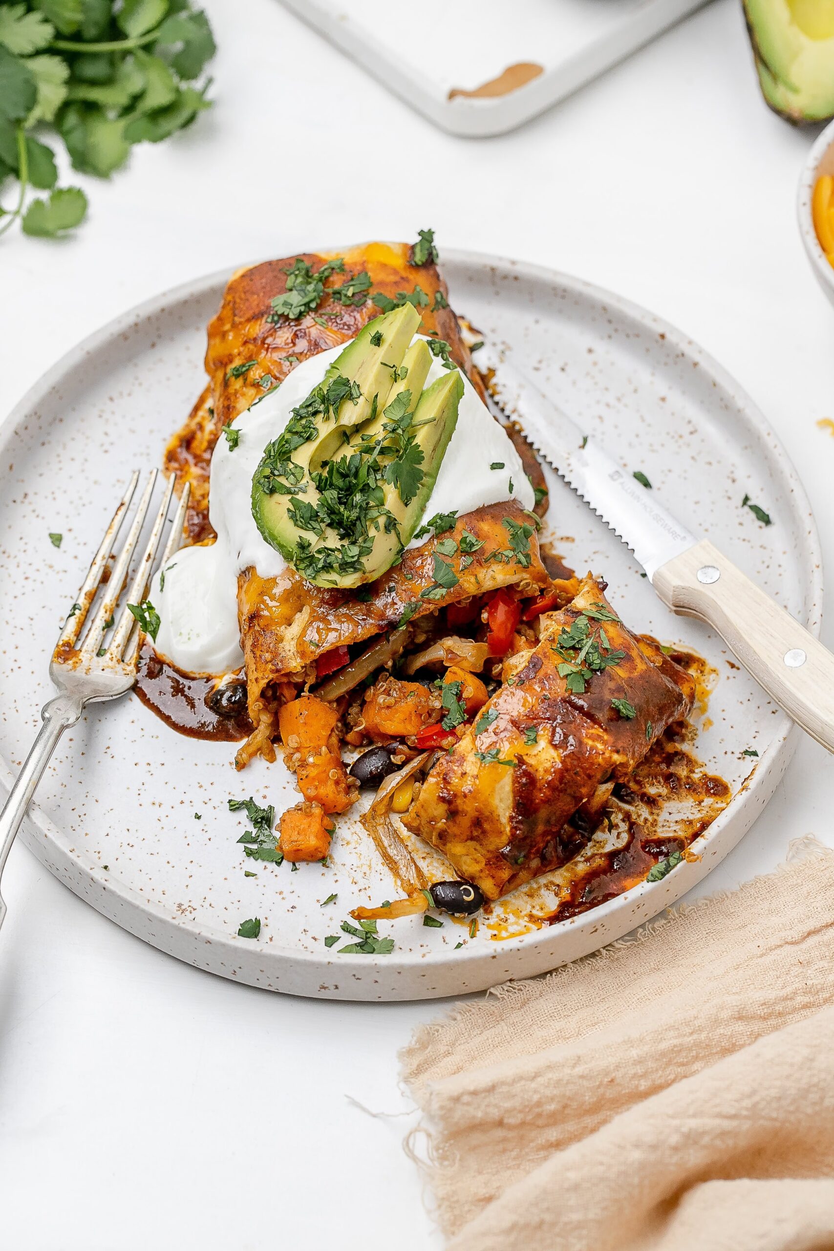 quinoa and veggie enchiladas on a plate with toppings.