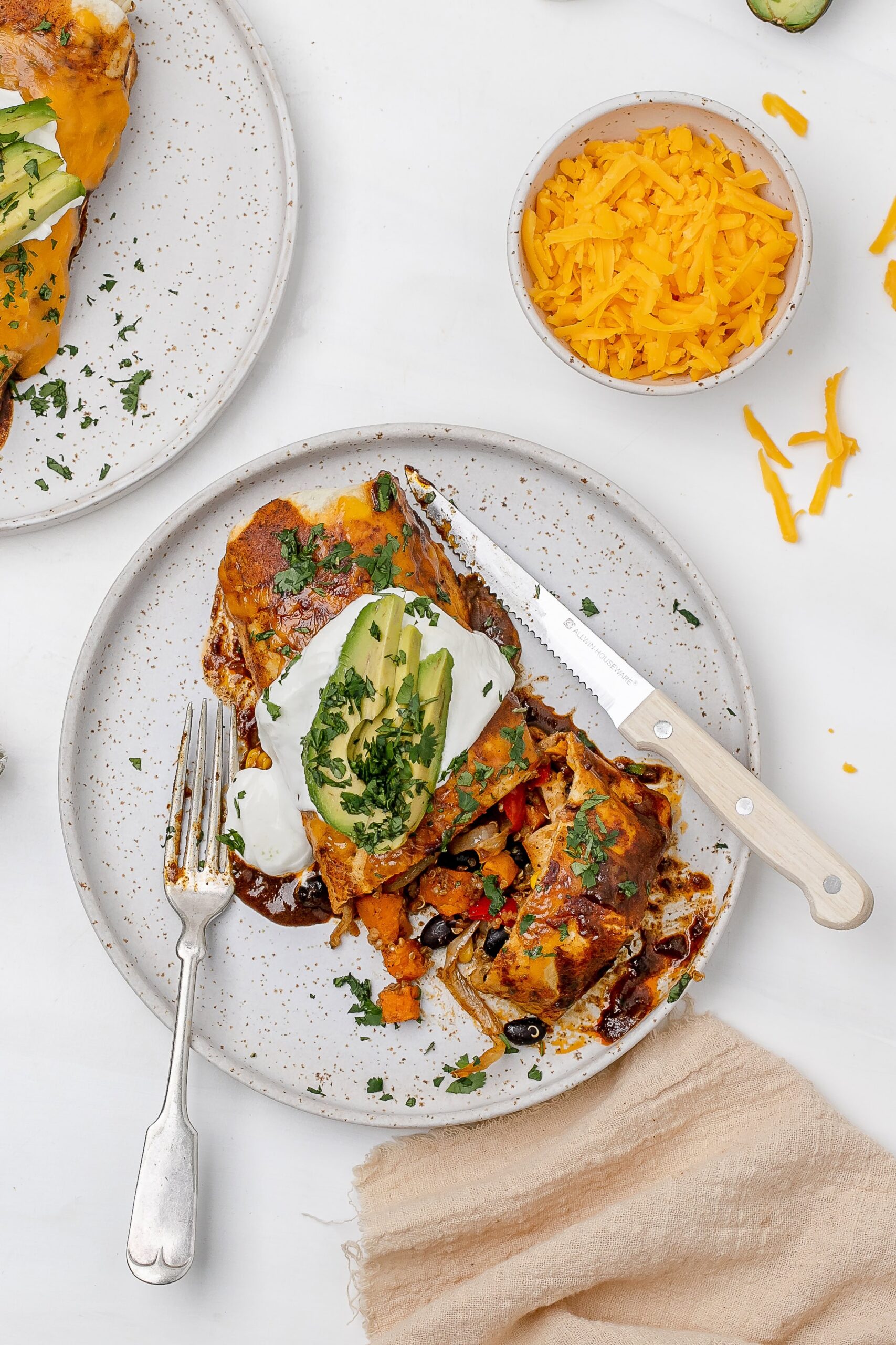 quinoa and veggie enchiladas on a plate with toppings.