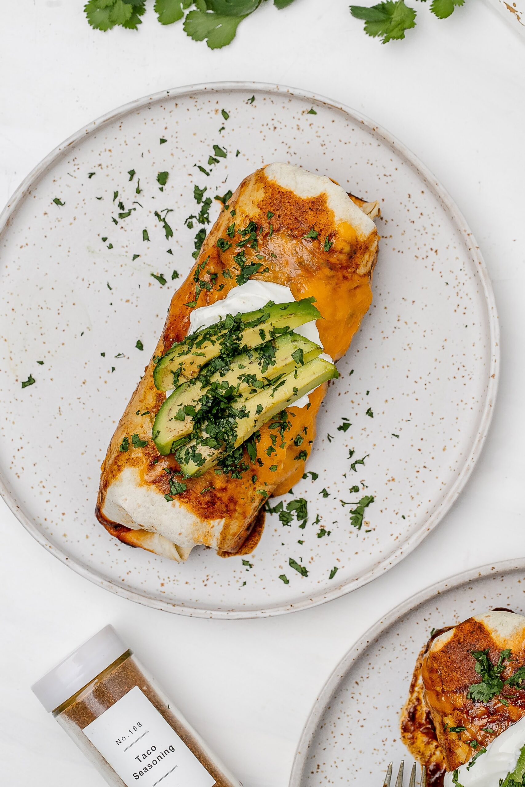 quinoa and veggie enchiladas on a plate with toppings.