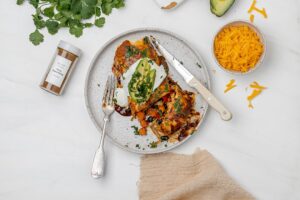 quinoa and veggie enchiladas on a plate with toppings.