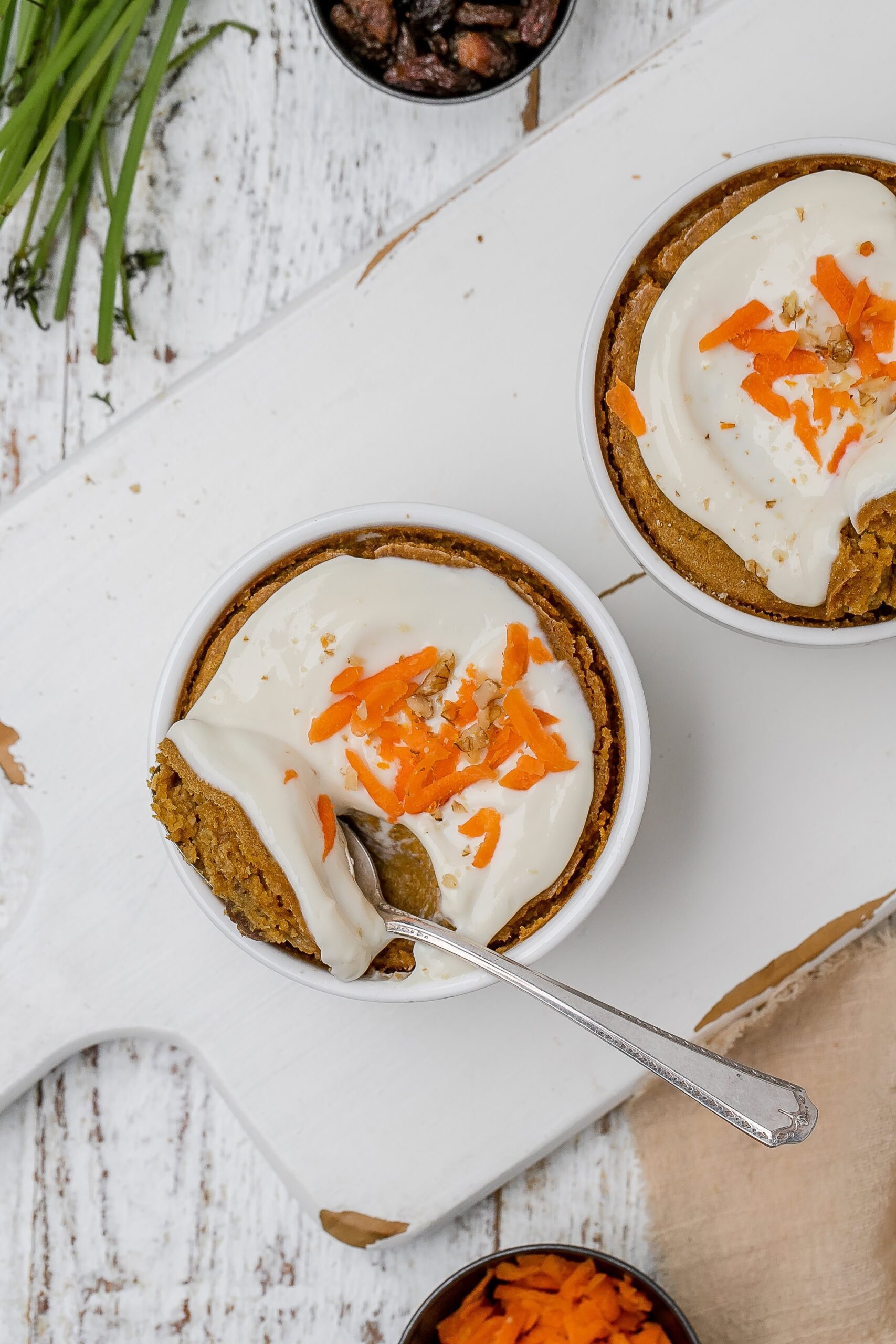 carrot cake baked oats with icing on top in ramekins.