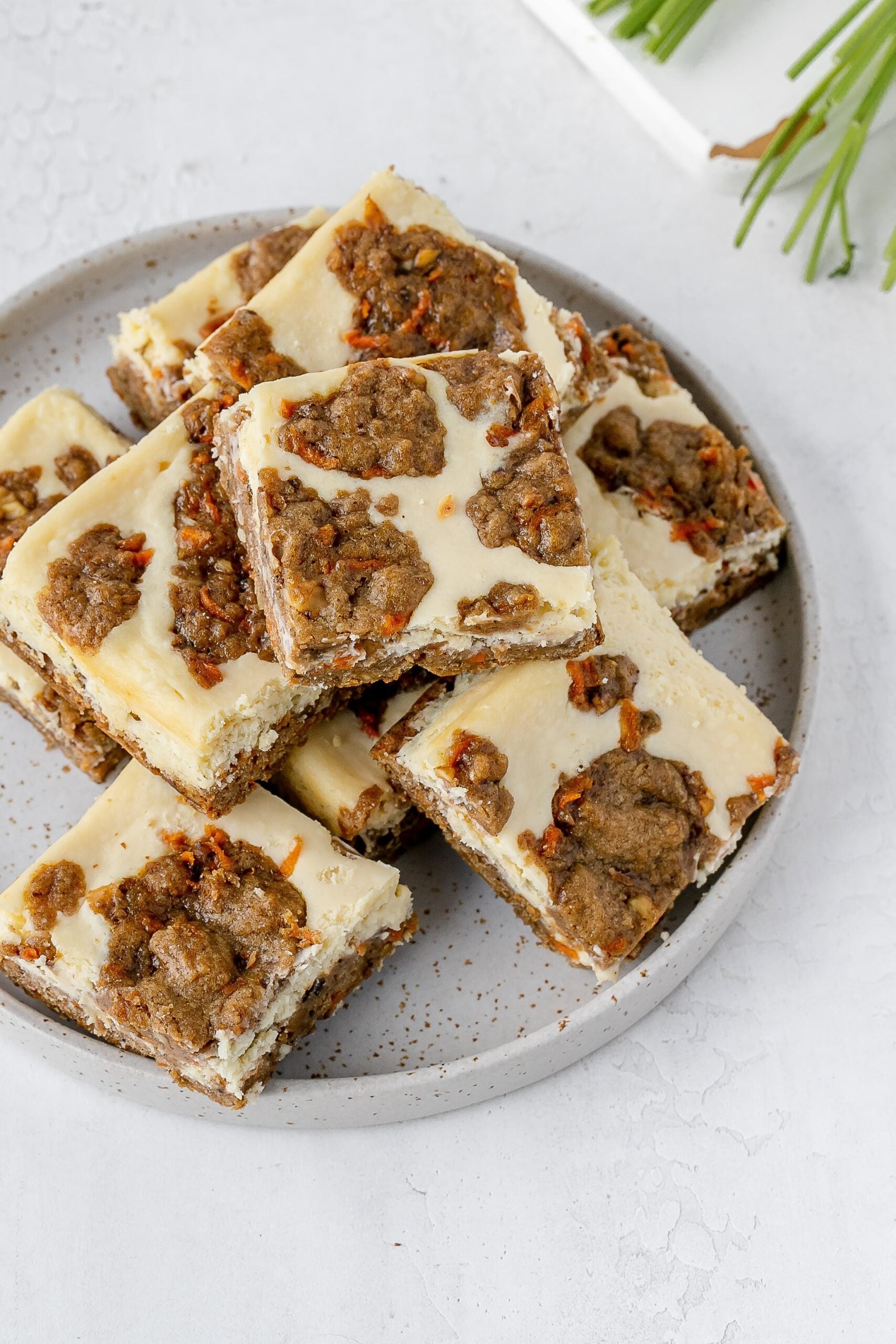 carrot cake cookie bars with cheesecake swirl on a plate.