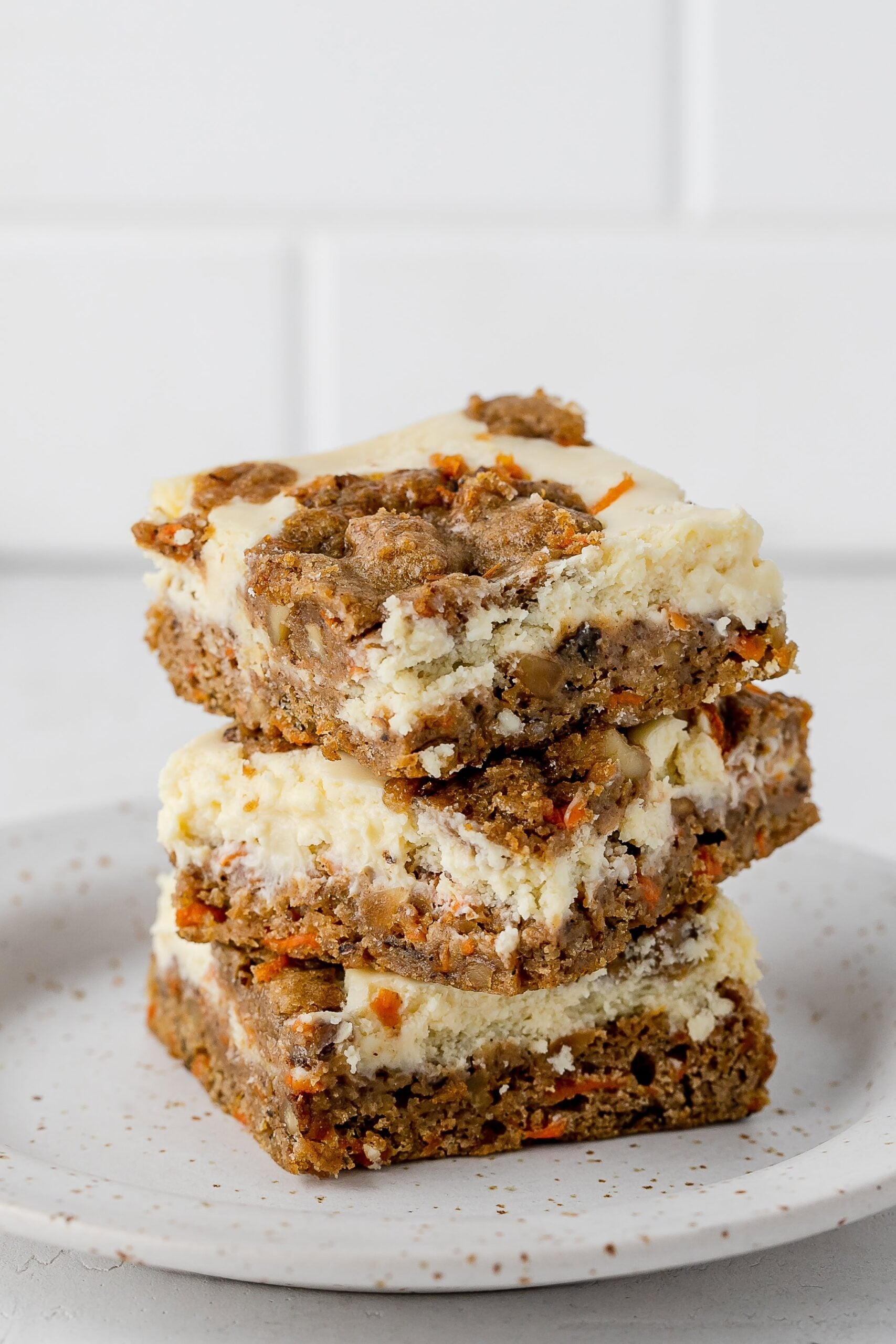 carrot cake cookie bars with cheesecake swirl on a plate.