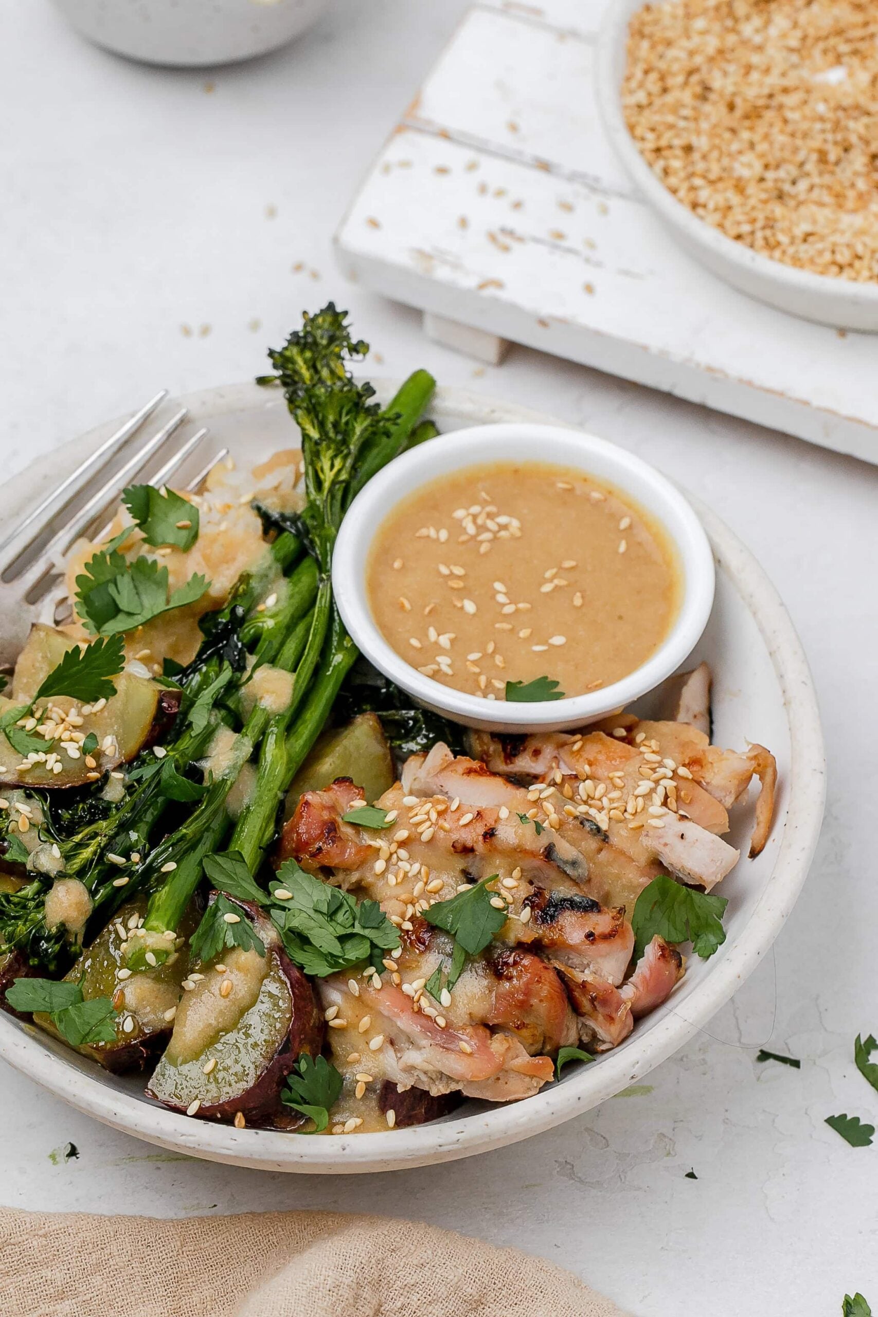 miso butter chicken thighs in a bowl with rice and veggies.