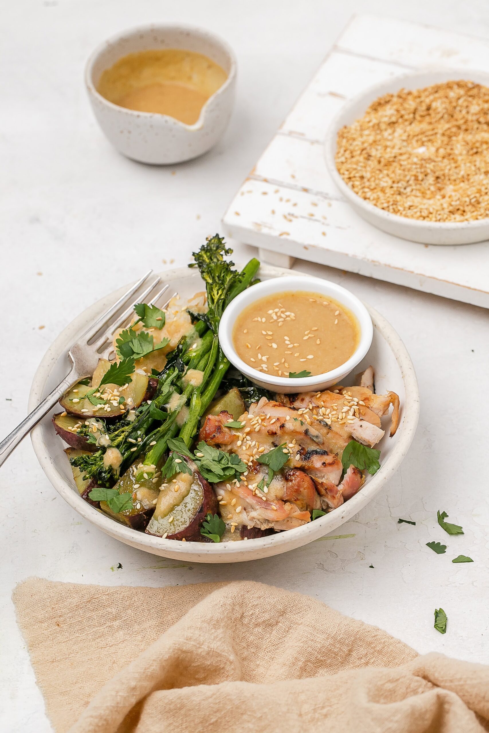 miso butter chicken thighs in a bowl with rice and veggies.
