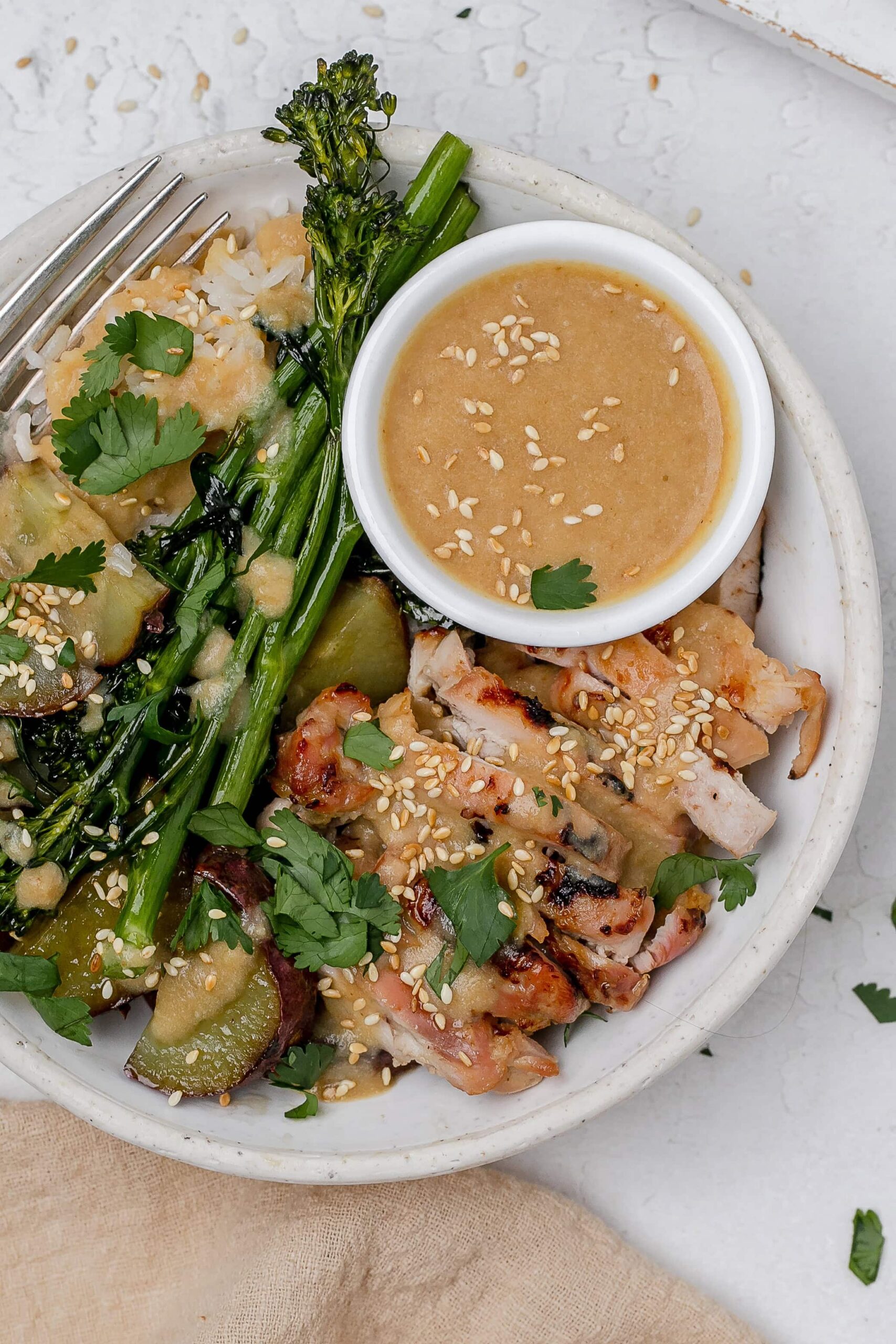 miso butter chicken thighs in a bowl with rice and veggies.