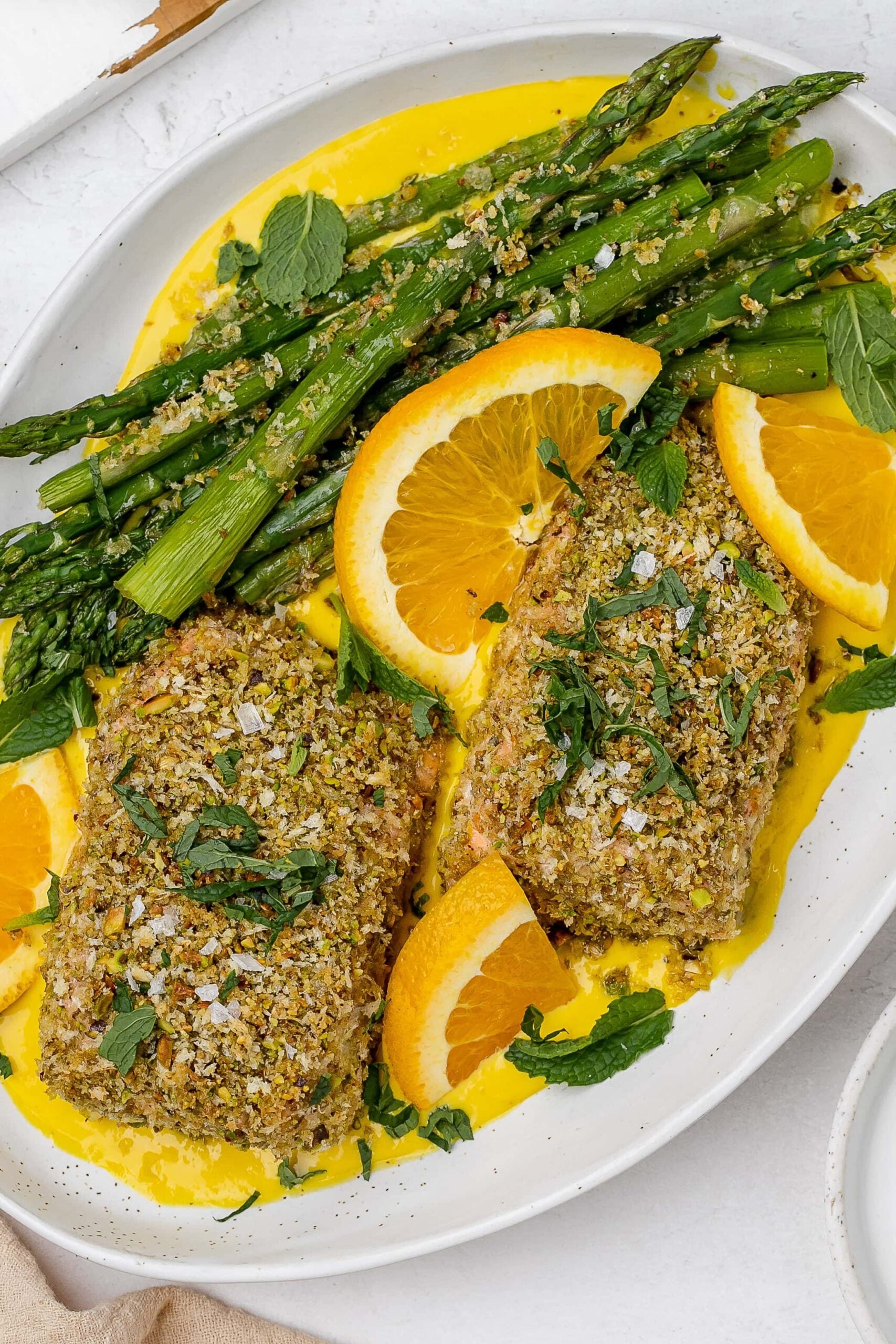 panko crusted salmon with saffron sauce on a platter with asparagus. 