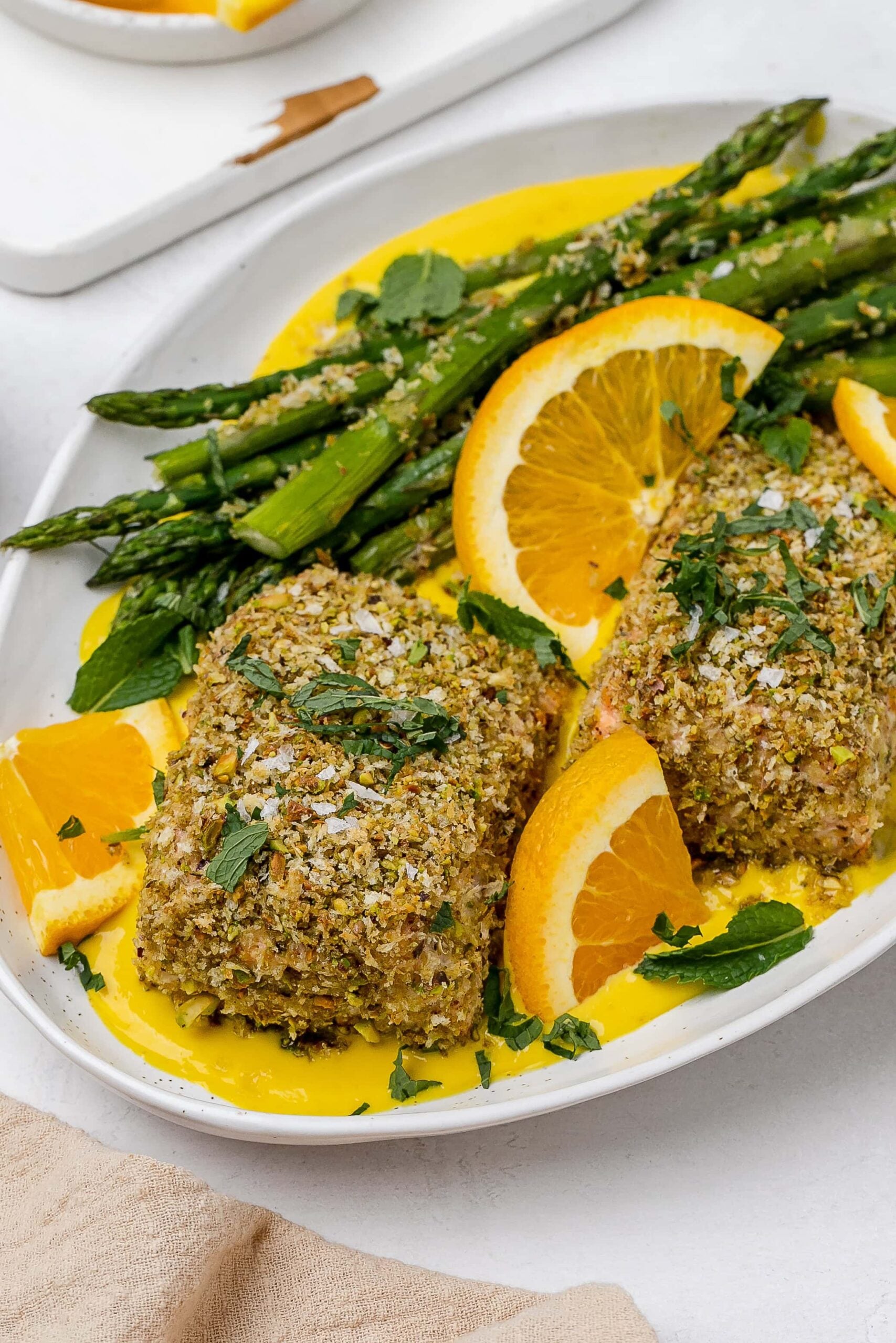 panko crusted salmon with saffron sauce on a platter with asparagus. 