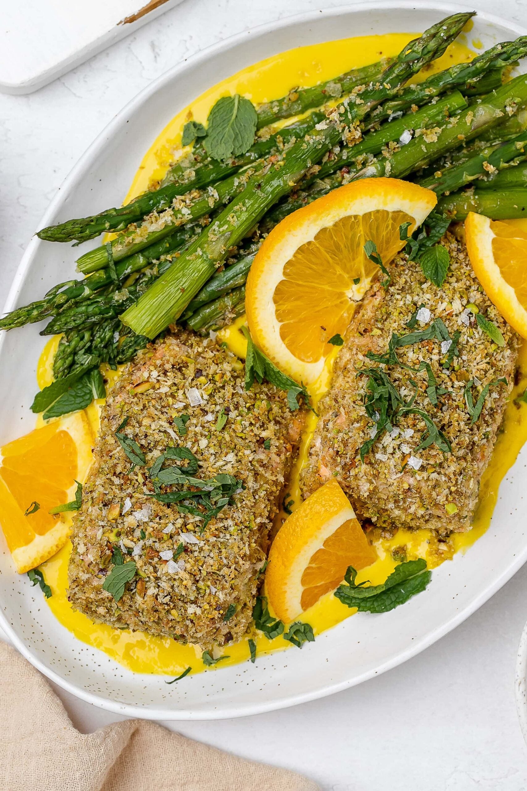 panko crusted salmon with saffron sauce on a platter with asparagus. 