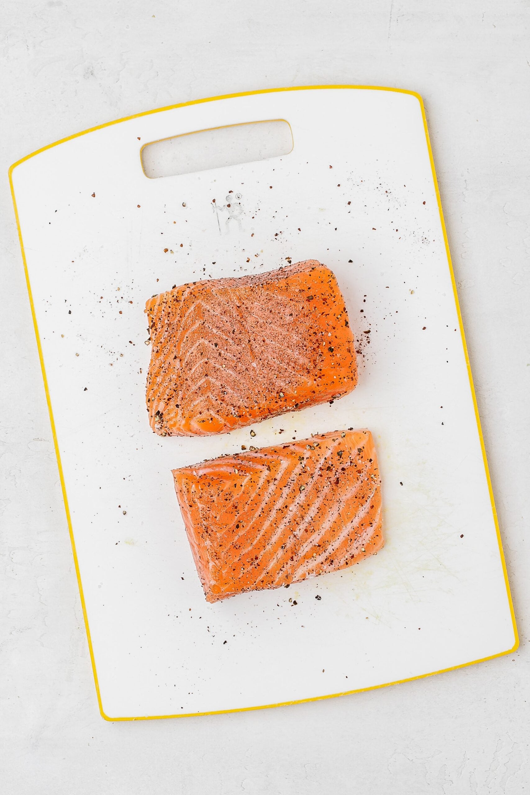 salmon fillet with seasoning on cutting board.