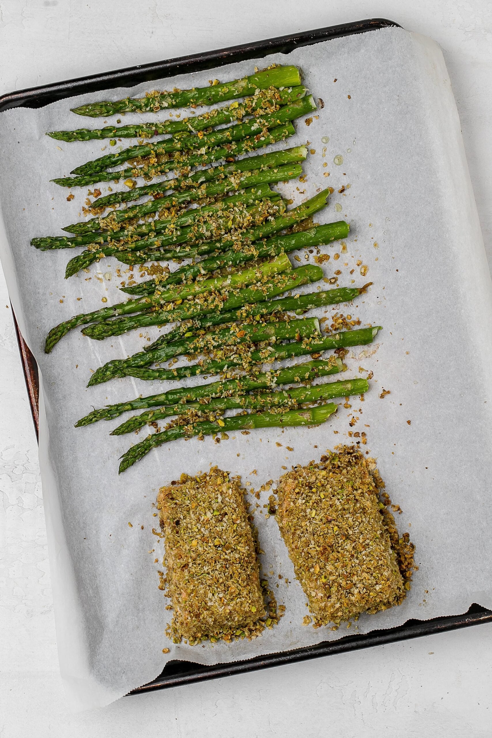 baked panko crusted salmon with asparagus on baking sheet.