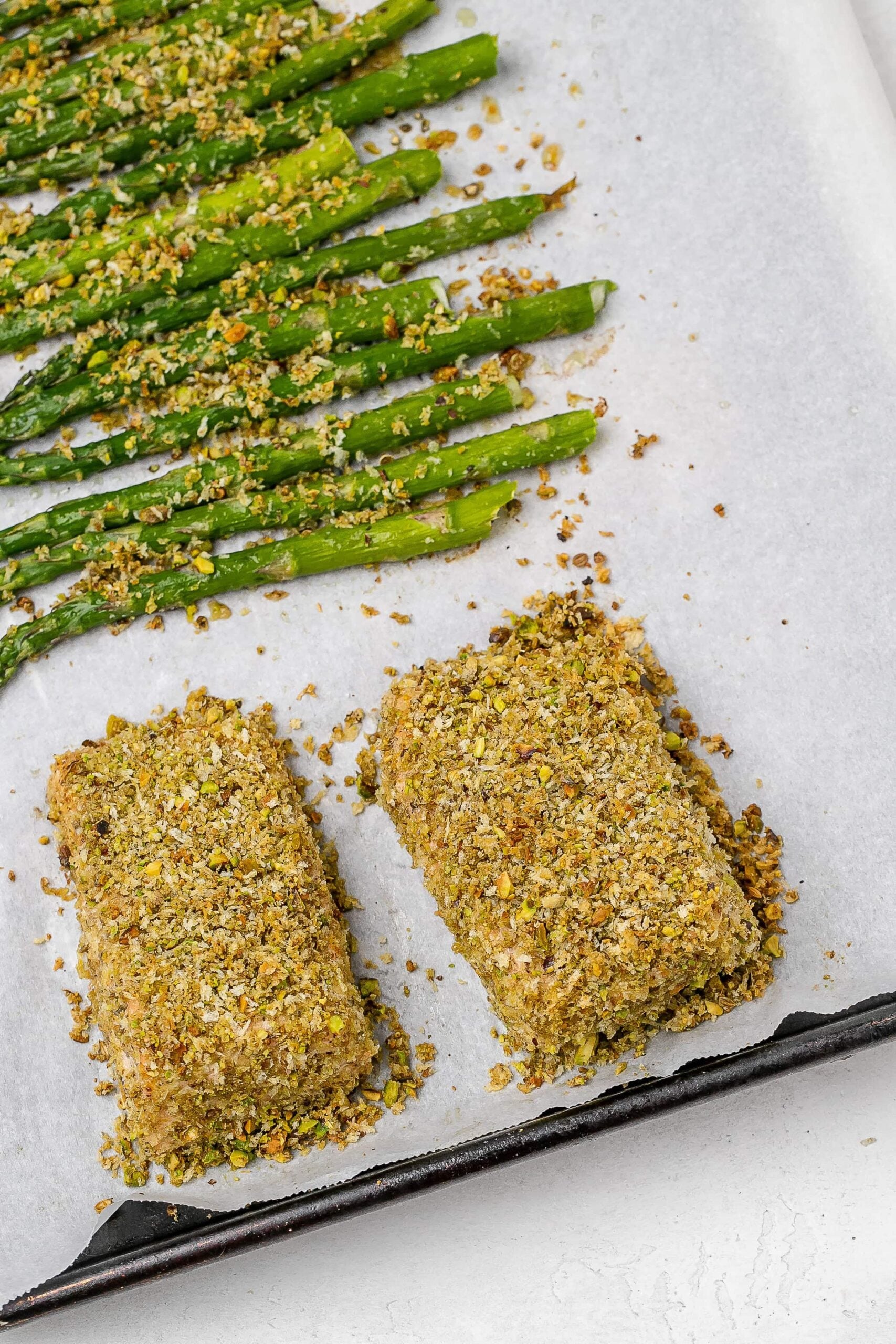panko crusted salmon on baking sheet with asparagus. 