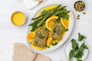 panko crusted salmon with saffron sauce on a platter with asparagus.