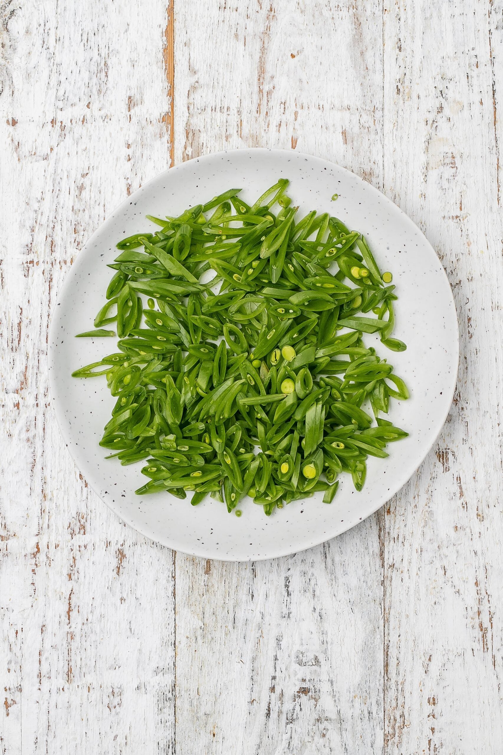 snap peas sliced thin on a bias on a plate. 