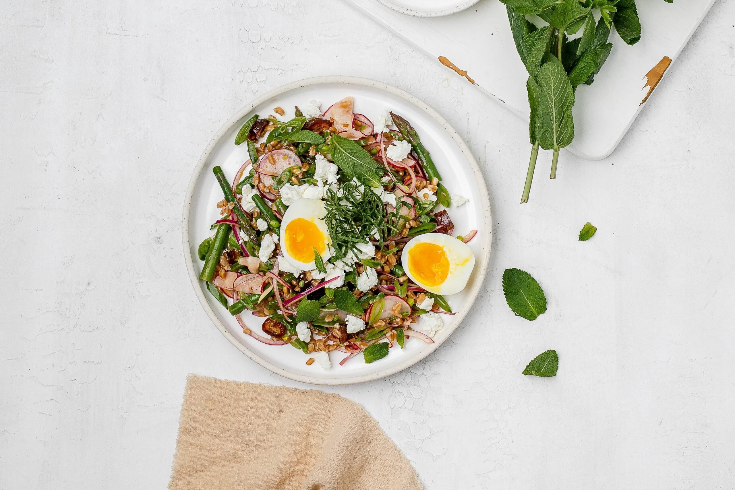 asparagus farro salad on a plate with a jammy egg.