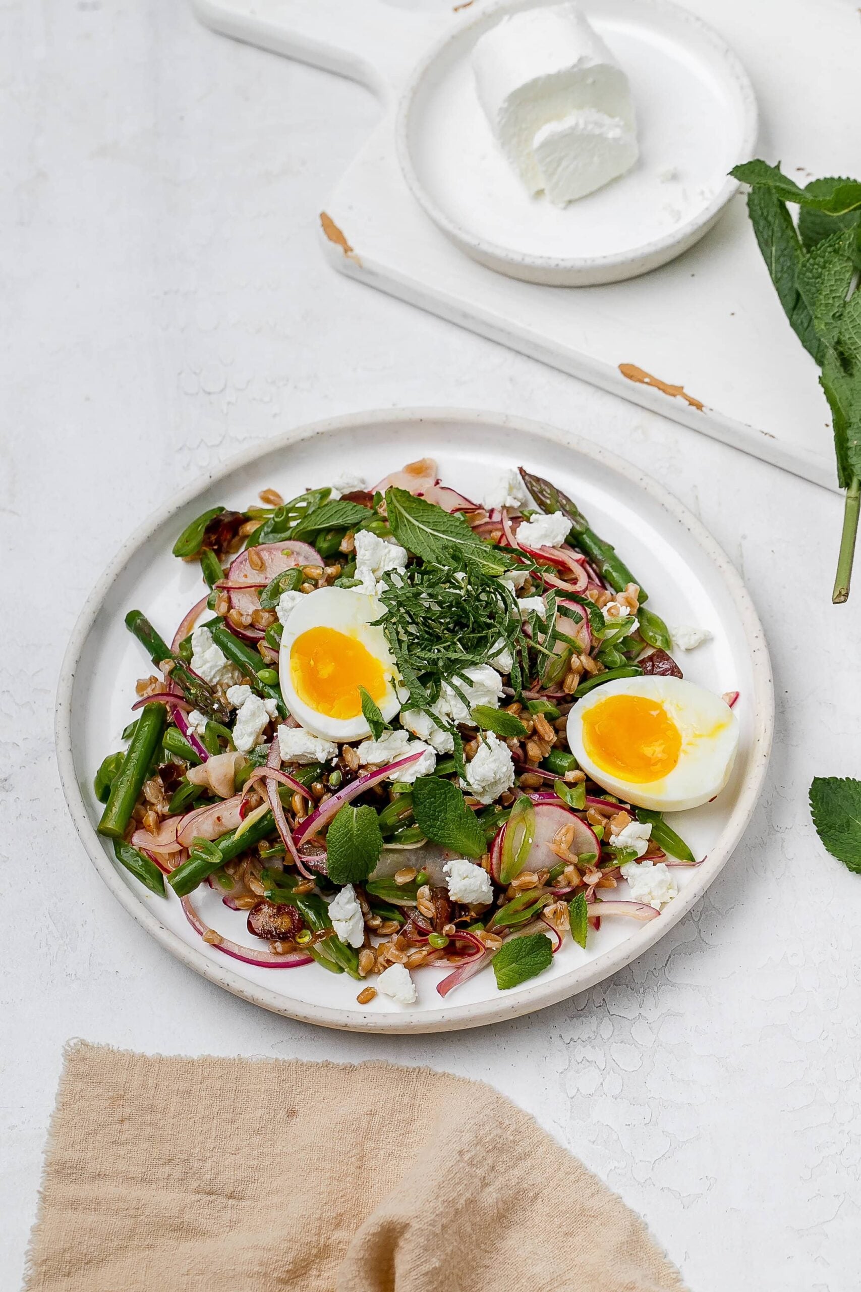 asparagus farro salad on a plate with a jammy egg.