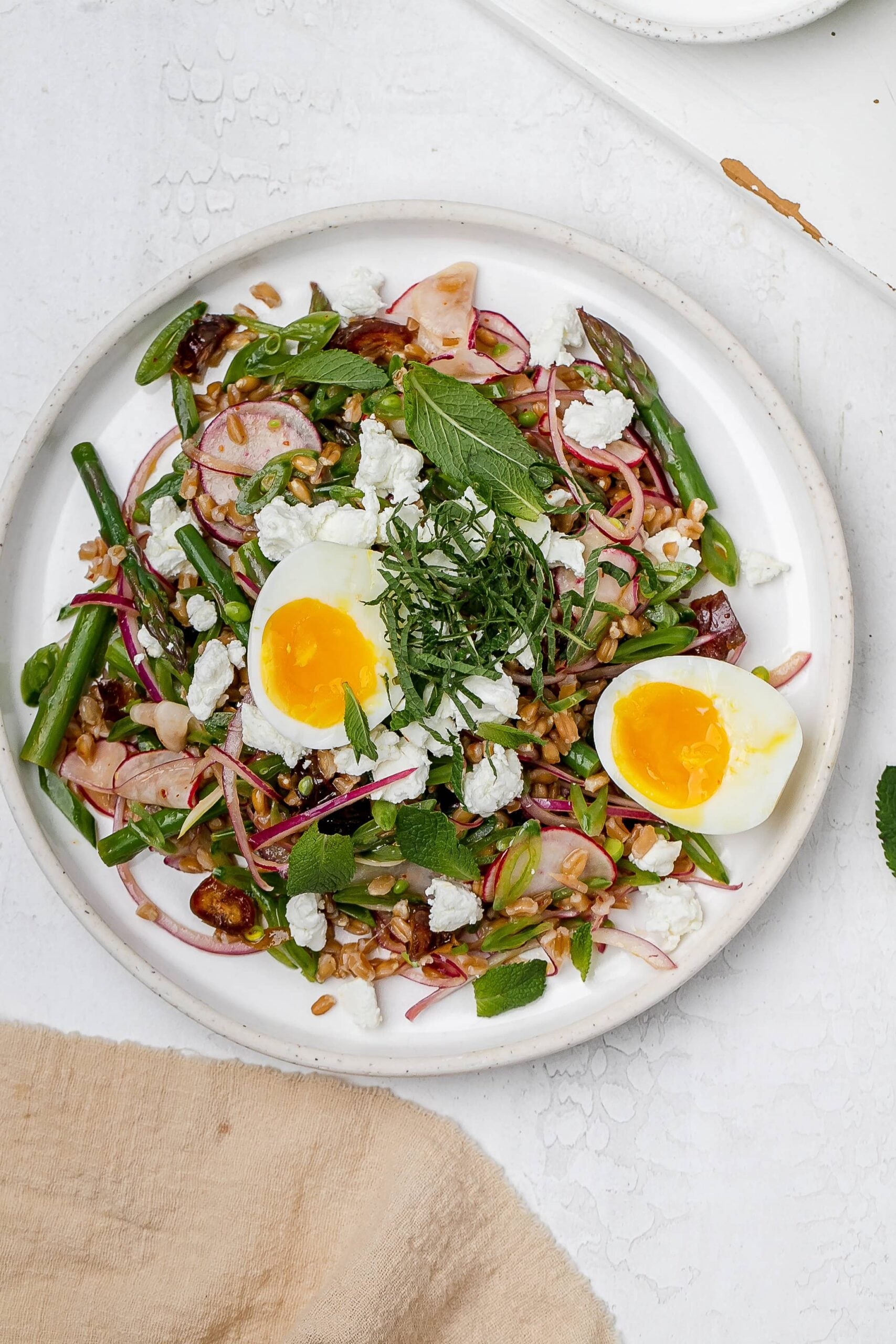 asparagus farro salad on a plate with a jammy egg.