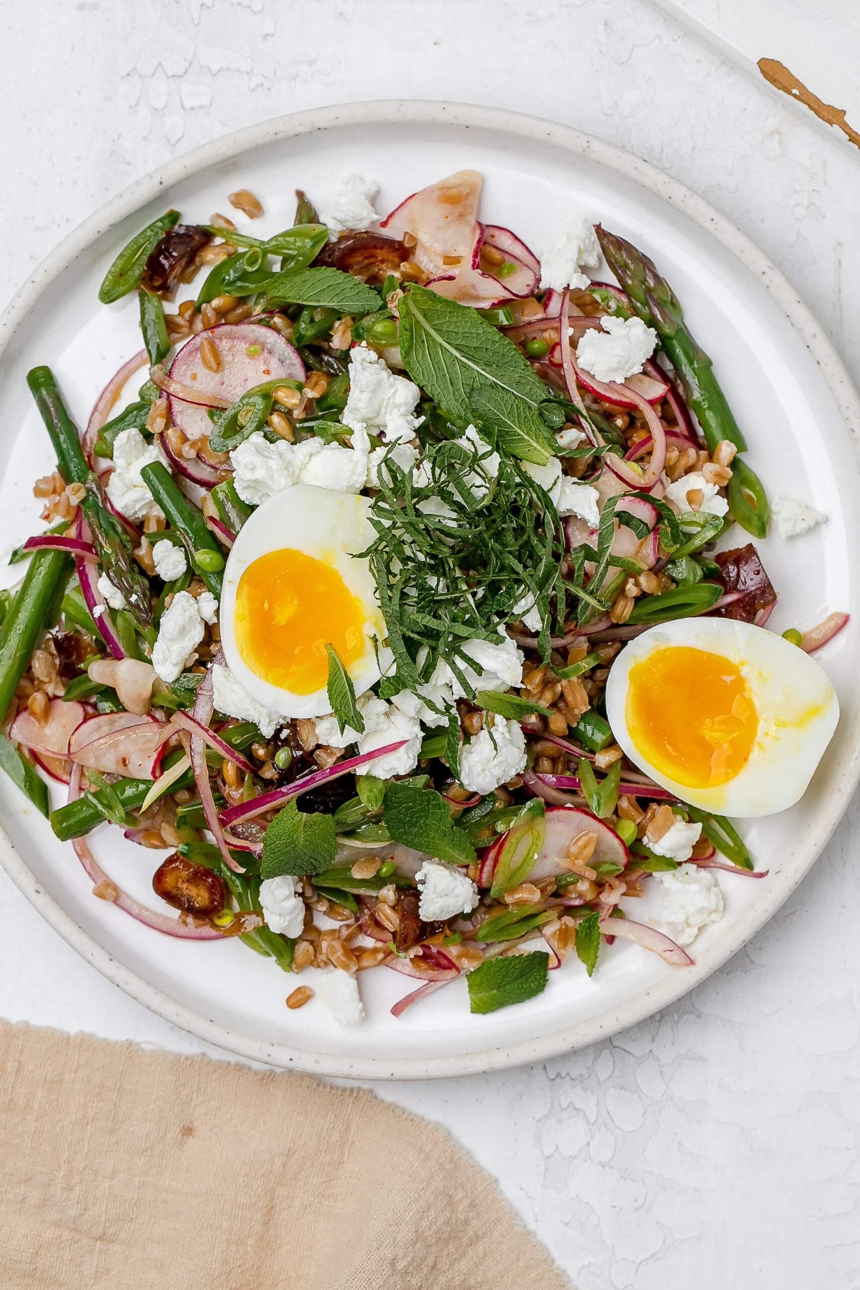 asparagus farro salad on a plate with a jammy egg.