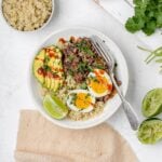 black bean, quinoa and egg breakfast bowl with avocado and hot sauce drizzled on top.