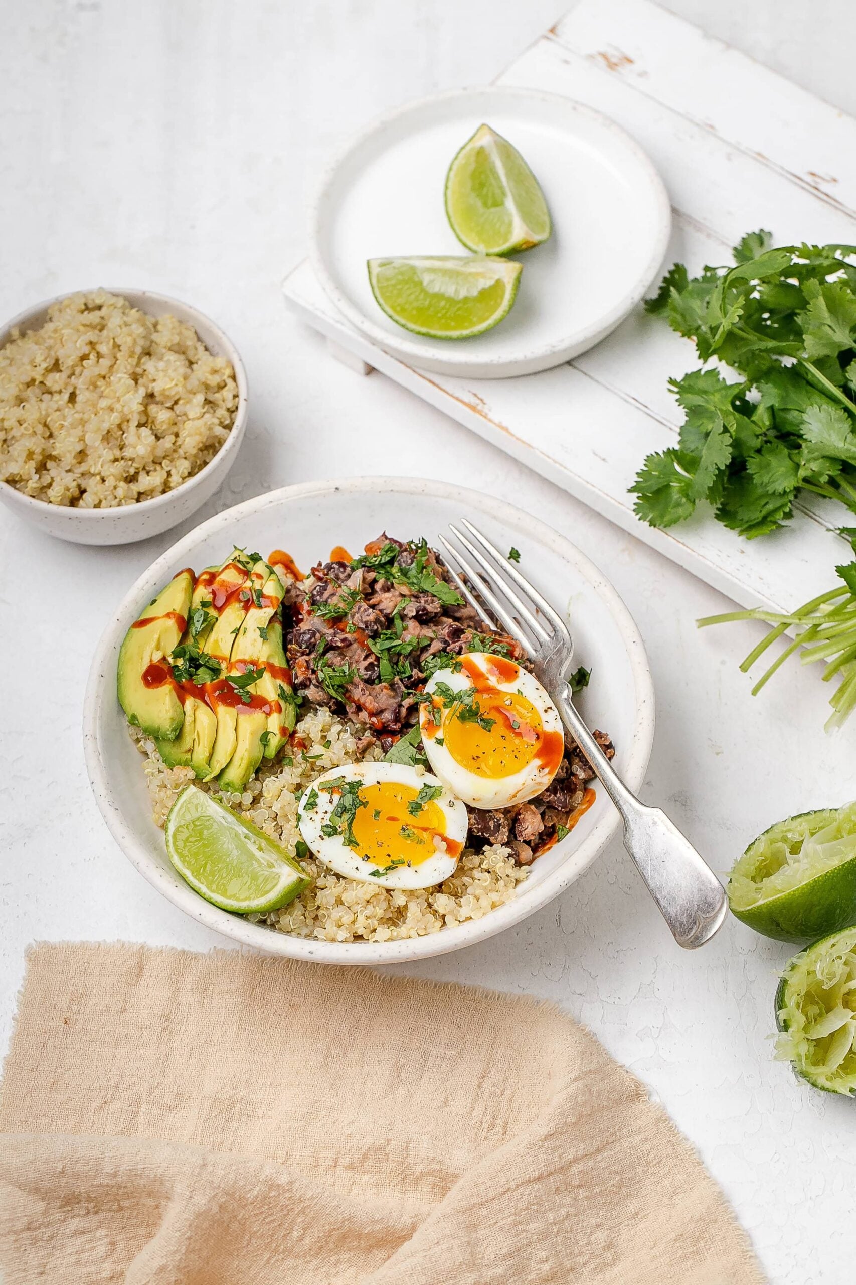 black bean, quinoa and egg breakfast bowl with avocado and hot sauce drizzled on top. 
