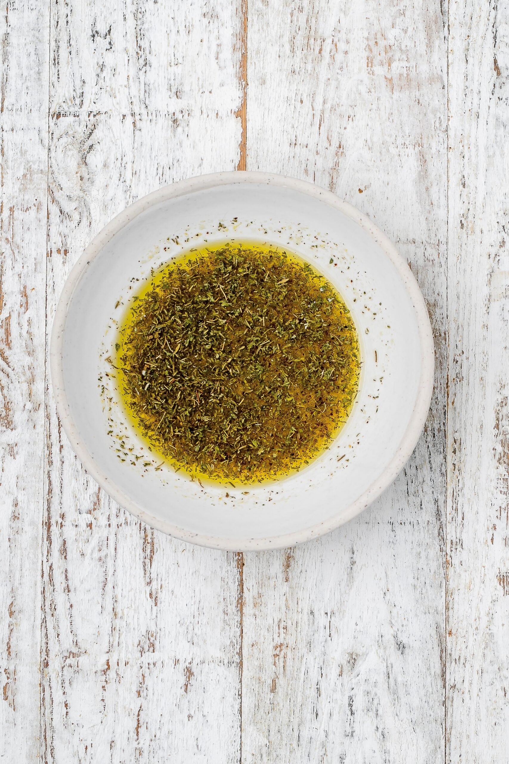 oil, lemon and herbs mixed together in a bowl. 
