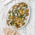 Greek smashed potatoes on a platter with dill and feta.