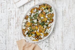 Greek smashed potatoes on a platter with dill and feta.