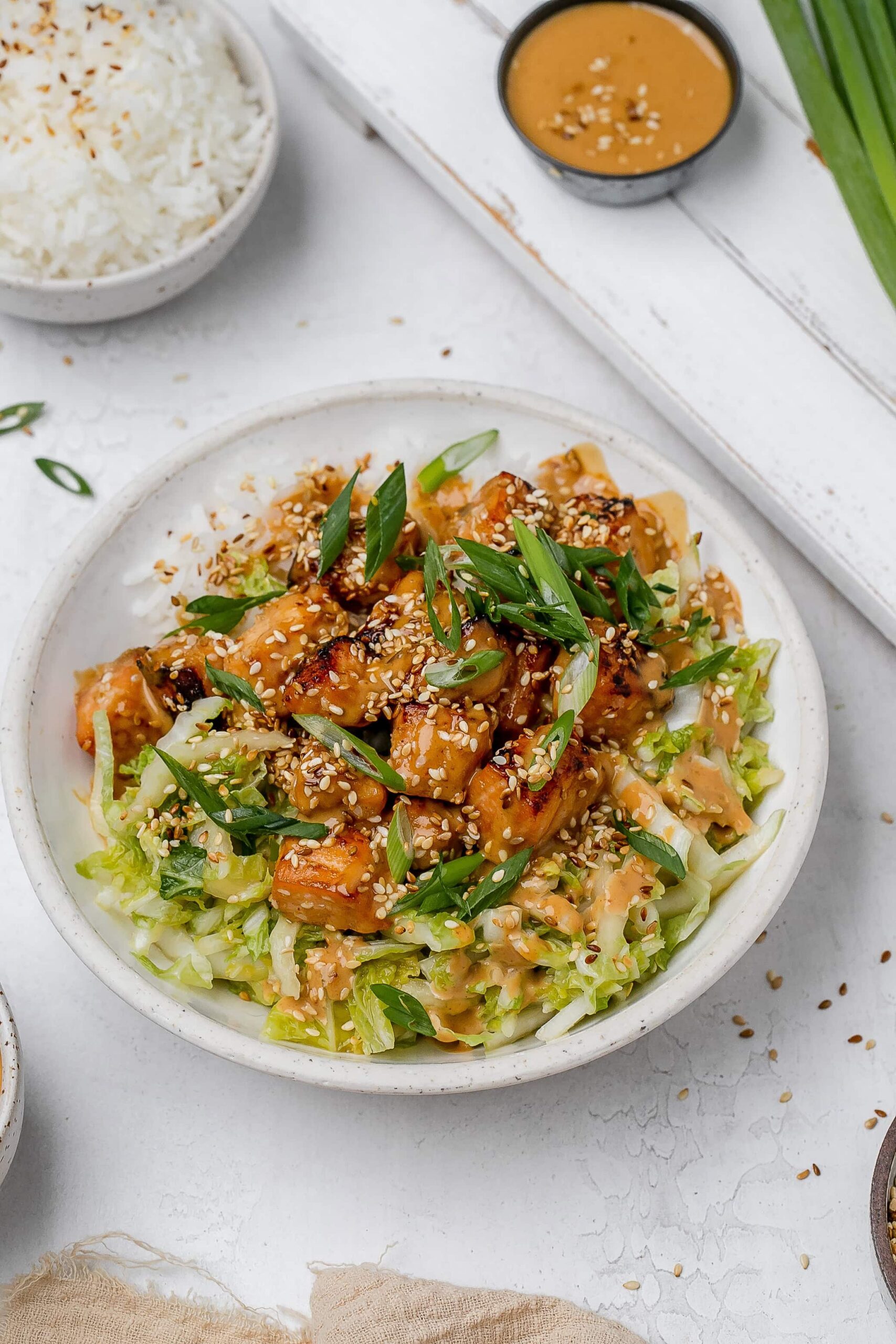 salmon with peanut sauce in a bowl with rice and cabbage slaw.