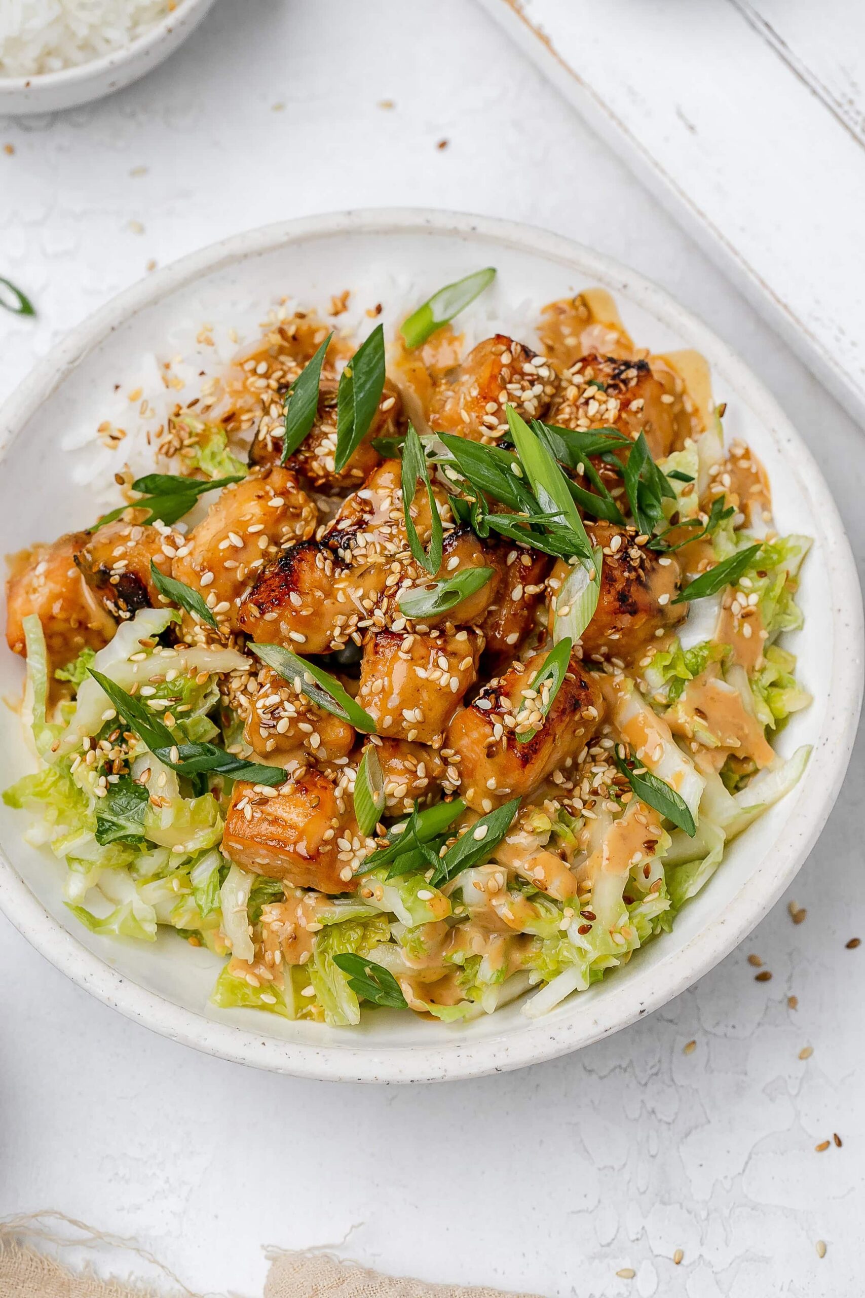 salmon with peanut sauce in a bowl with rice and cabbage slaw.