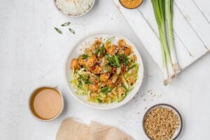 salmon with peanut sauce in a bowl with rice and cabbage slaw.