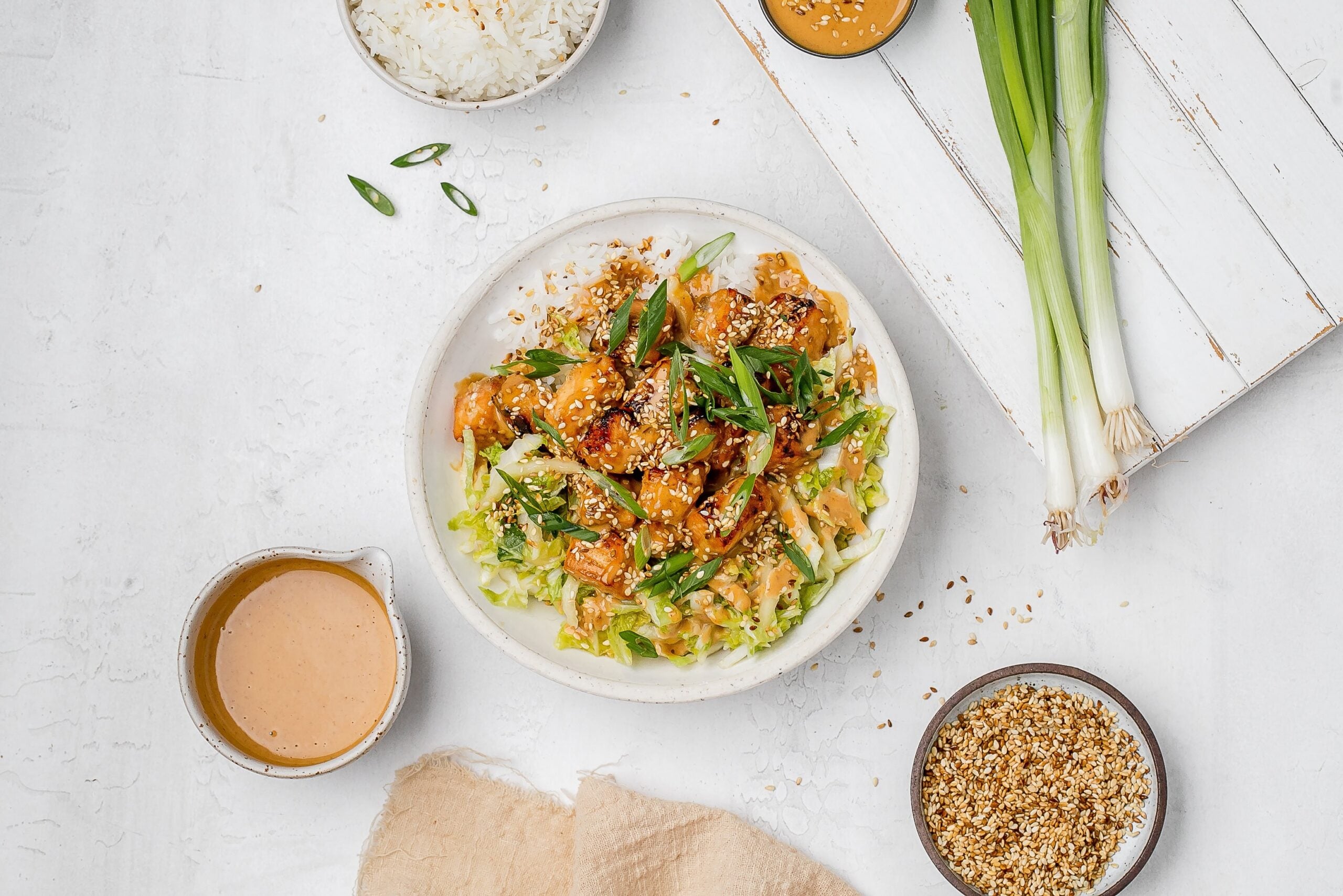 salmon with peanut sauce in a bowl with rice and cabbage slaw.