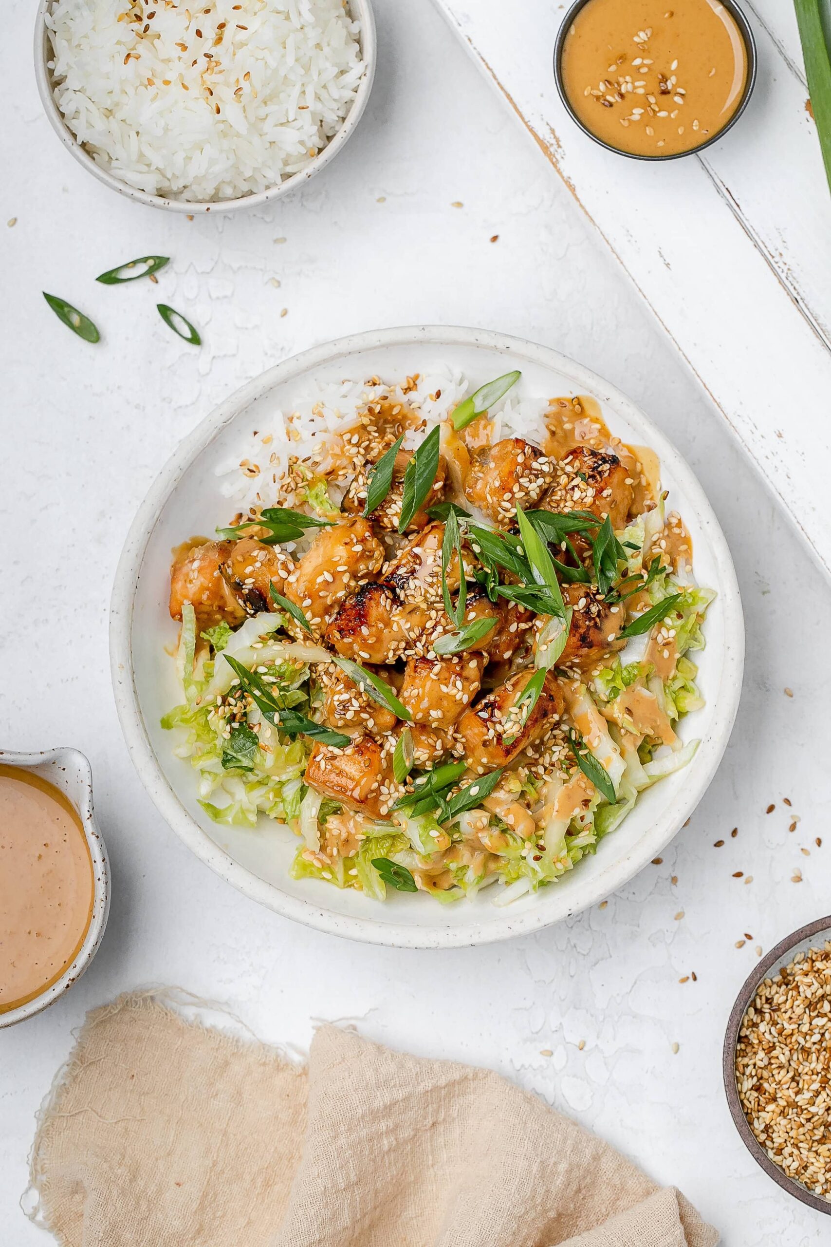 salmon with peanut sauce in a bowl with rice and cabbage slaw.