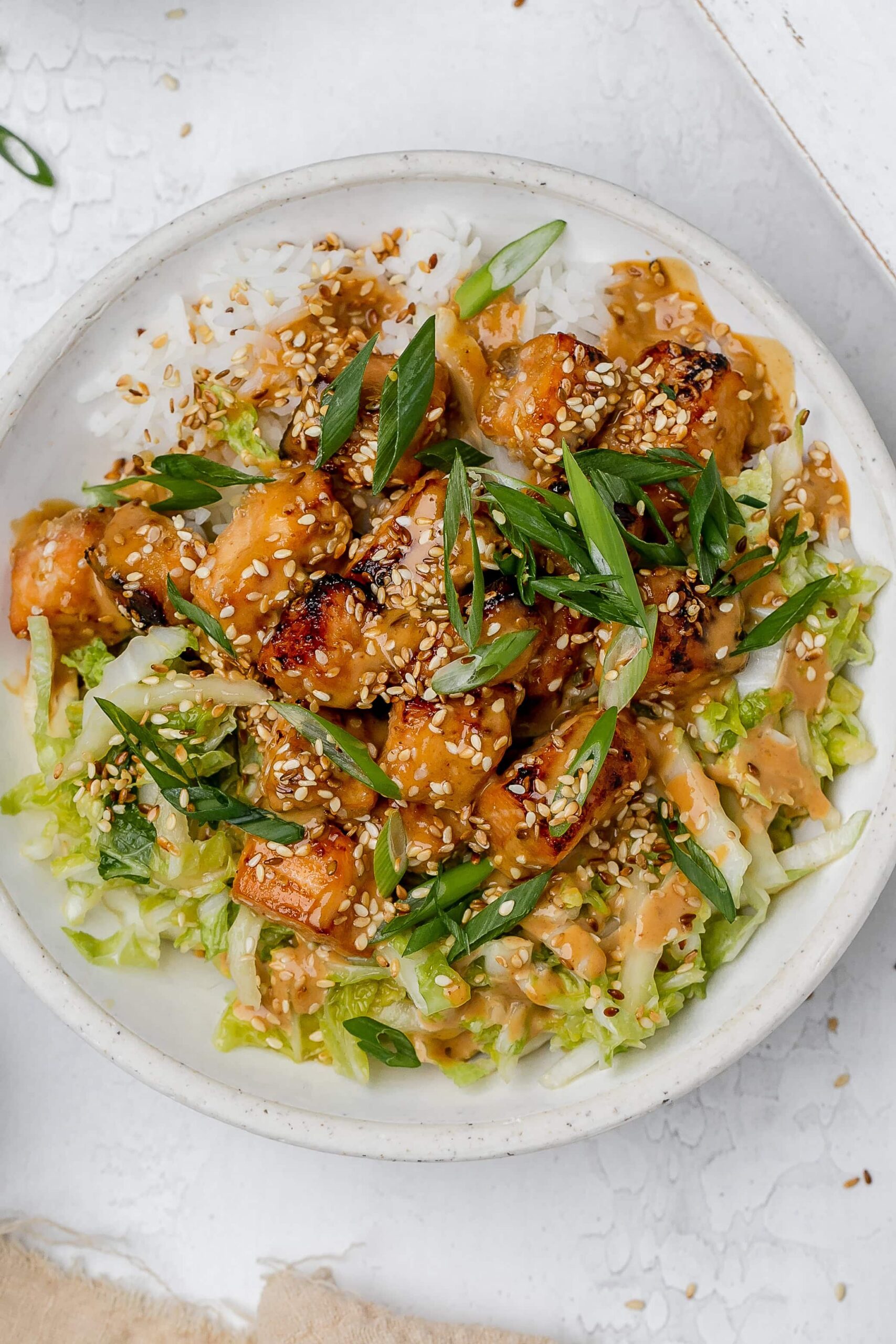 salmon with peanut sauce in a bowl with rice and cabbage slaw.