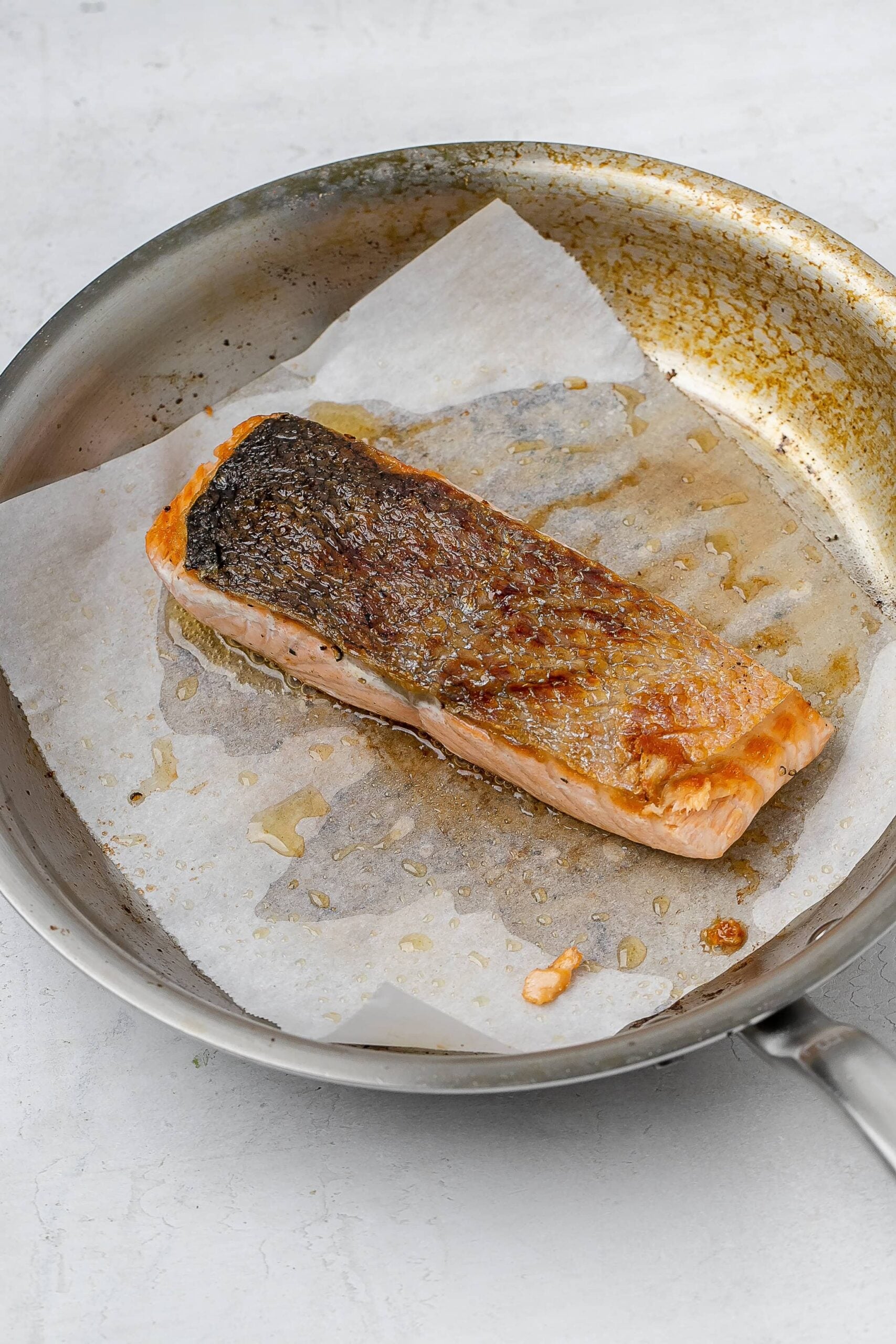 salmon in skillet with parchment paper.