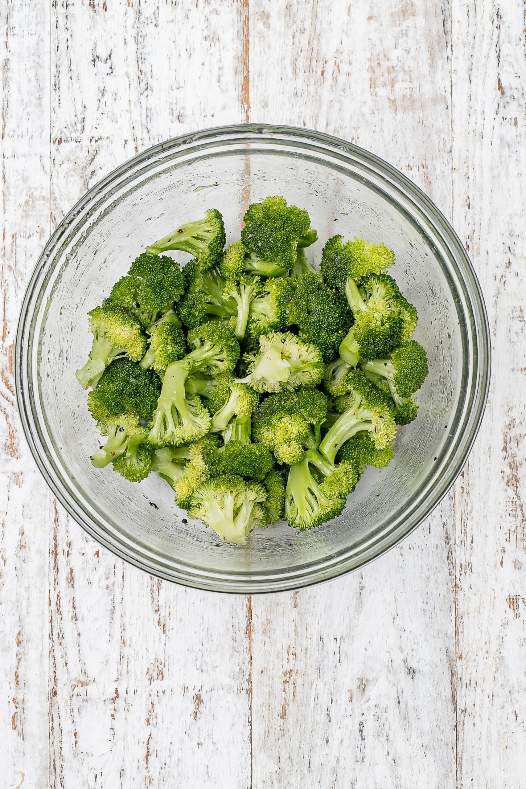 broccoli in a bowl with oil, salt and pepper.