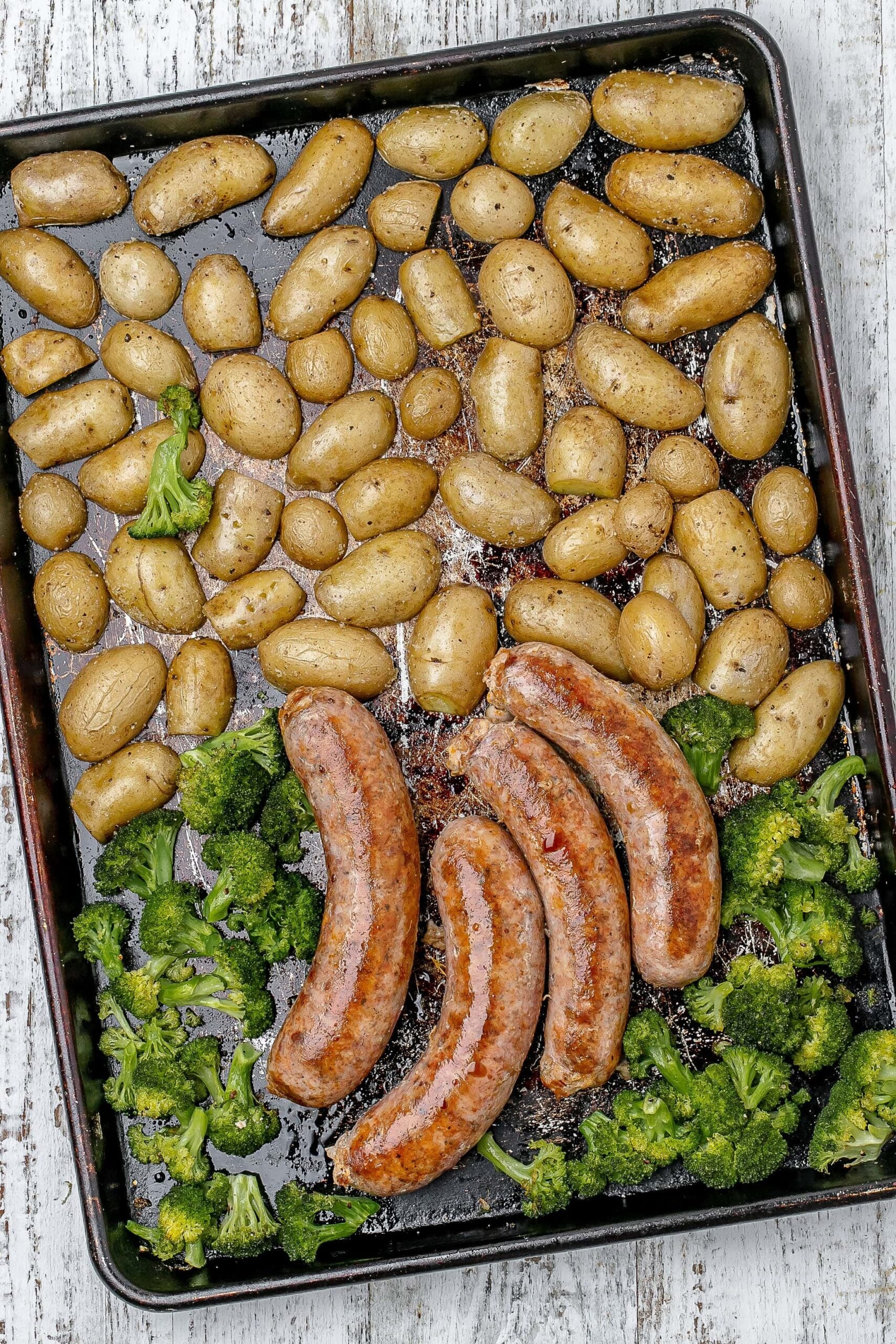 sausages added to sheet pan with potatoes and broccoli.