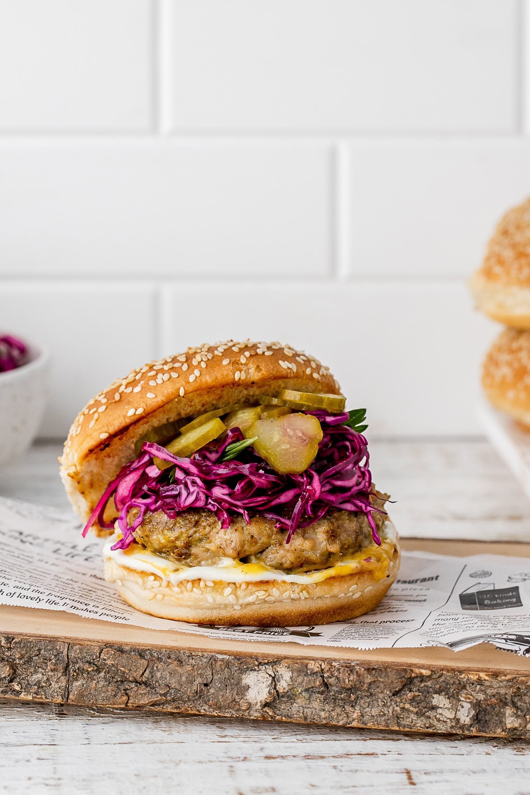 chicken shawarma burger with a bun and slaw on a plate. 