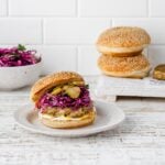 chicken shawarma burger with a bun and slaw on a plate.
